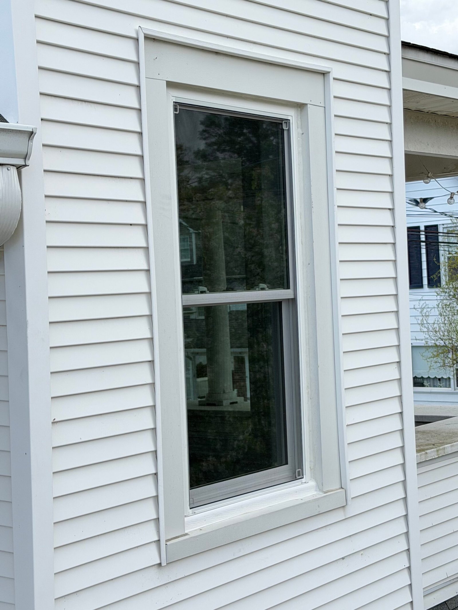 After: another completed single window within the surrounding white siding and trim.