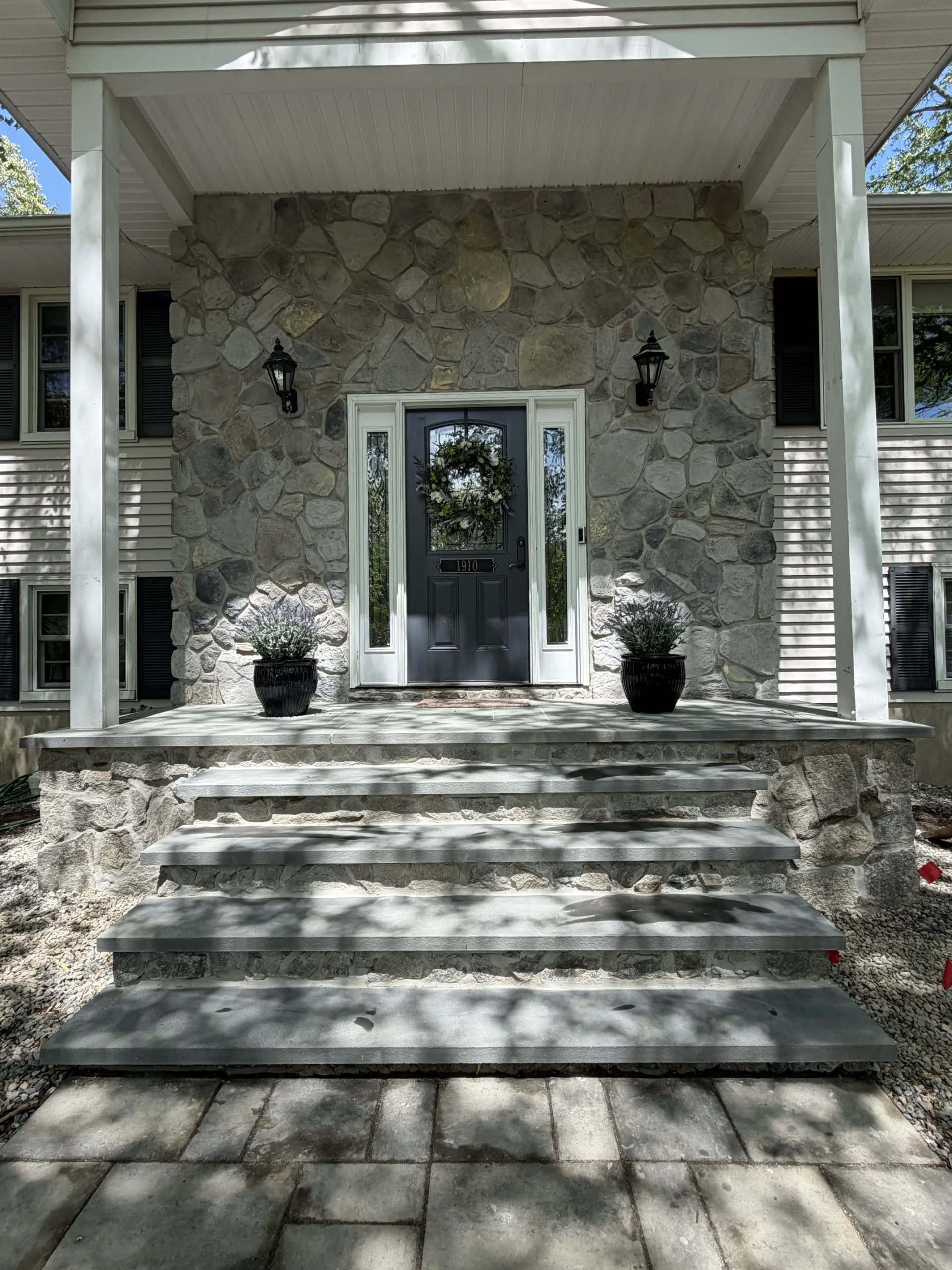Finished stone-faced porch and gray front stair treads