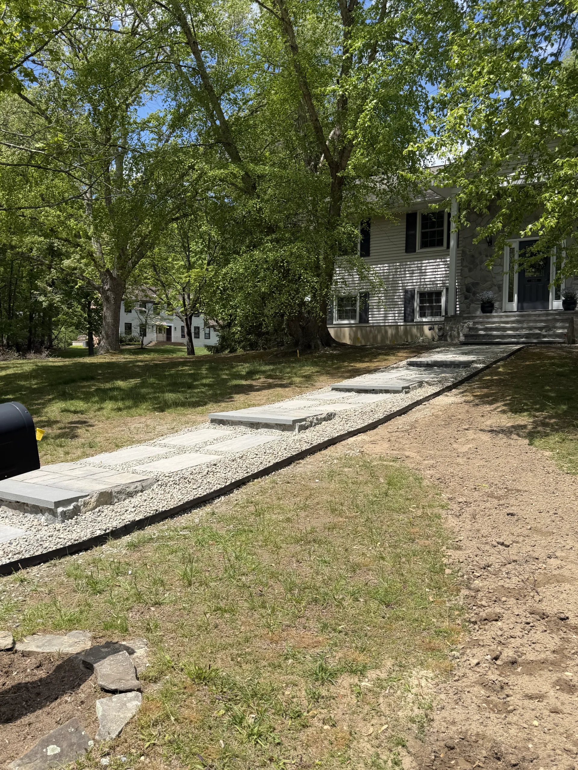 Finished walkway with gray slabs and gravel, viewed toward the house