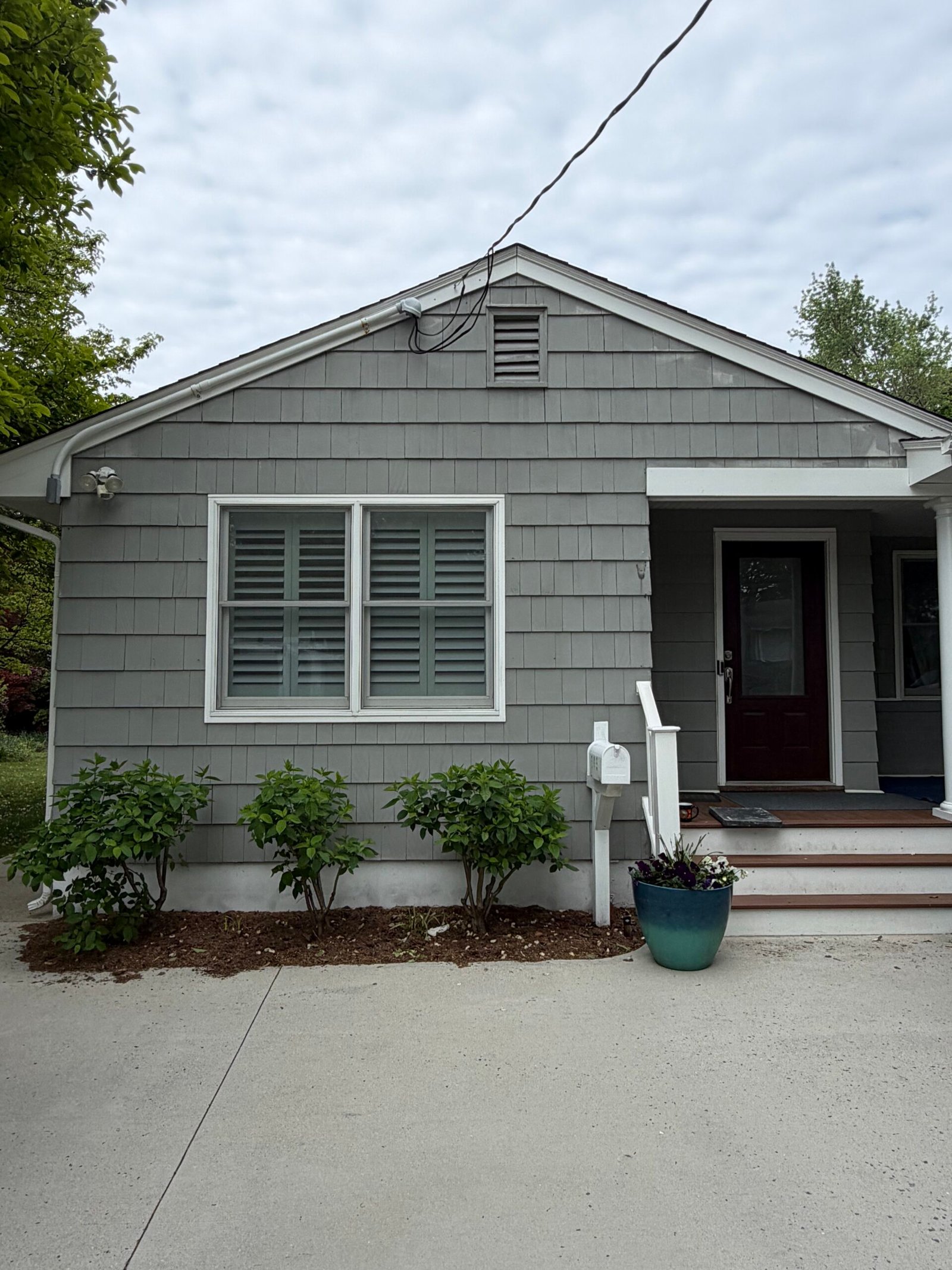 Before: the front gable, gray siding, white window trim and covered entrance.