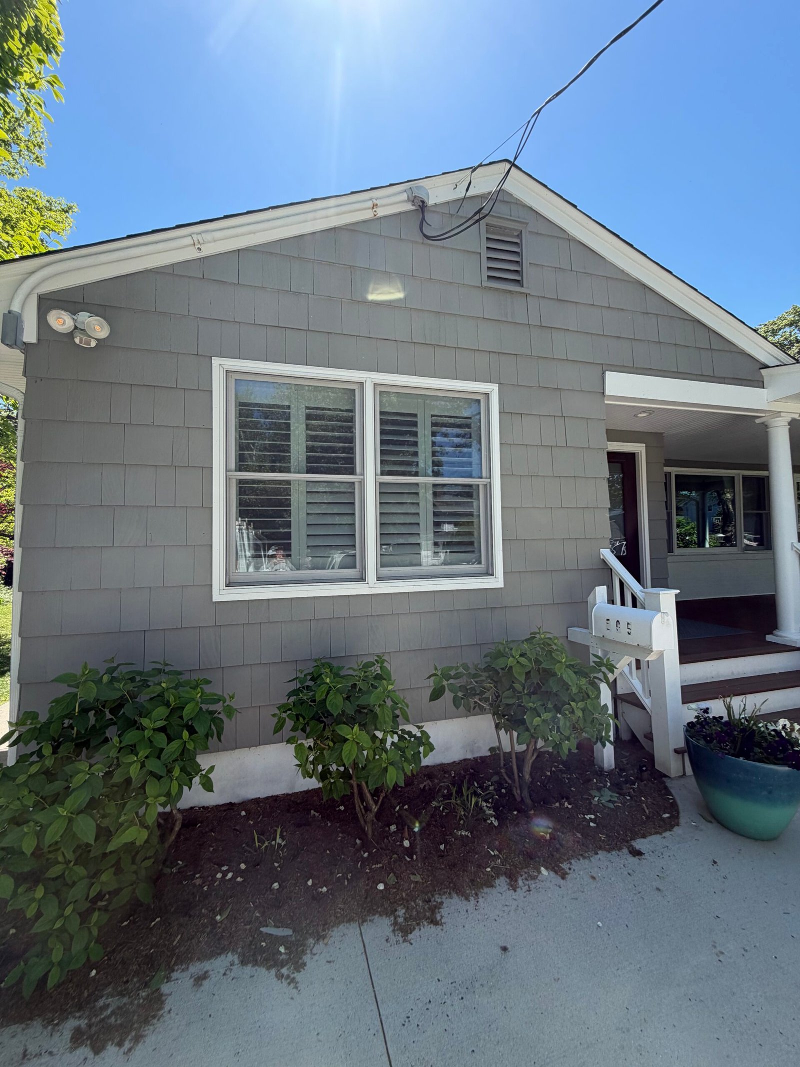 After: the repainted front elevation with gray siding and contrasting white details.