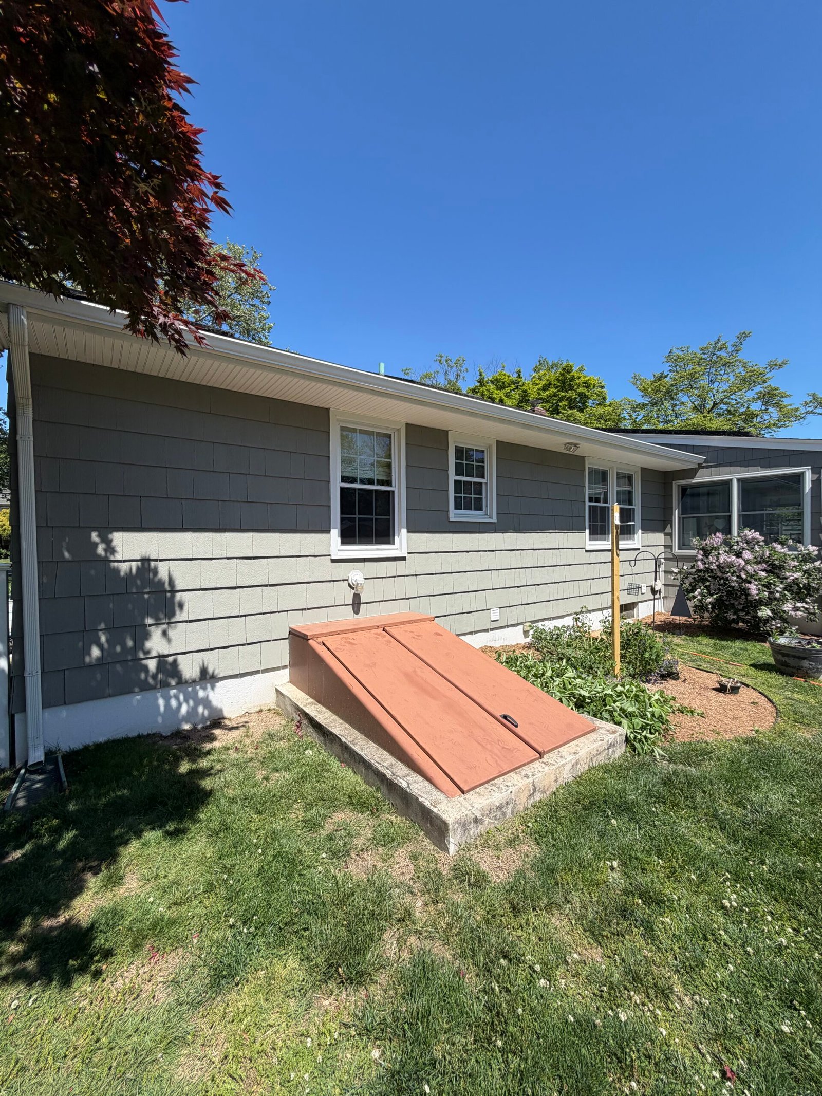 After: the rear wall and white window details beside the lawn and basement access.