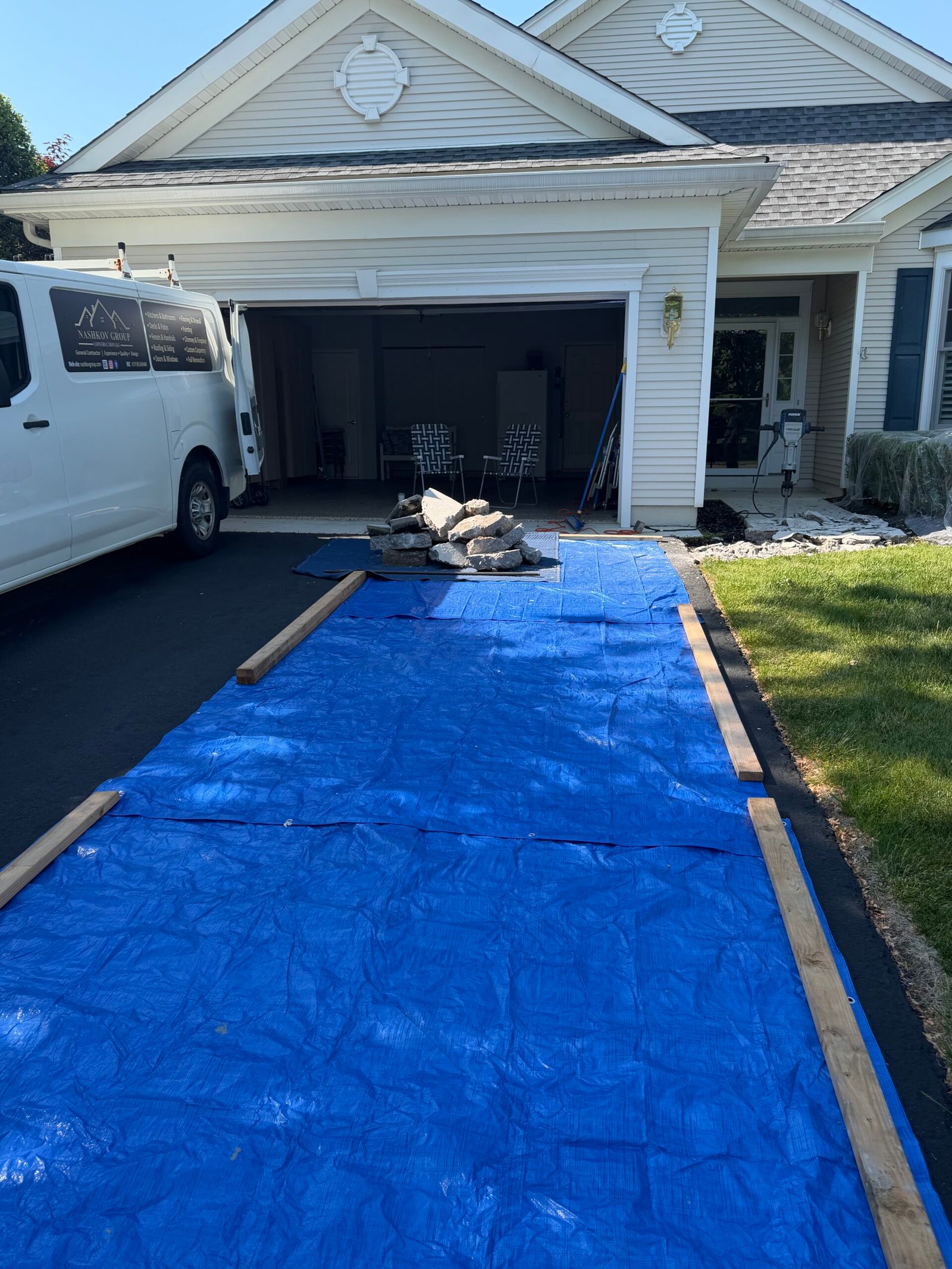A blue tarp protecting the adjacent driveway during the removal work.