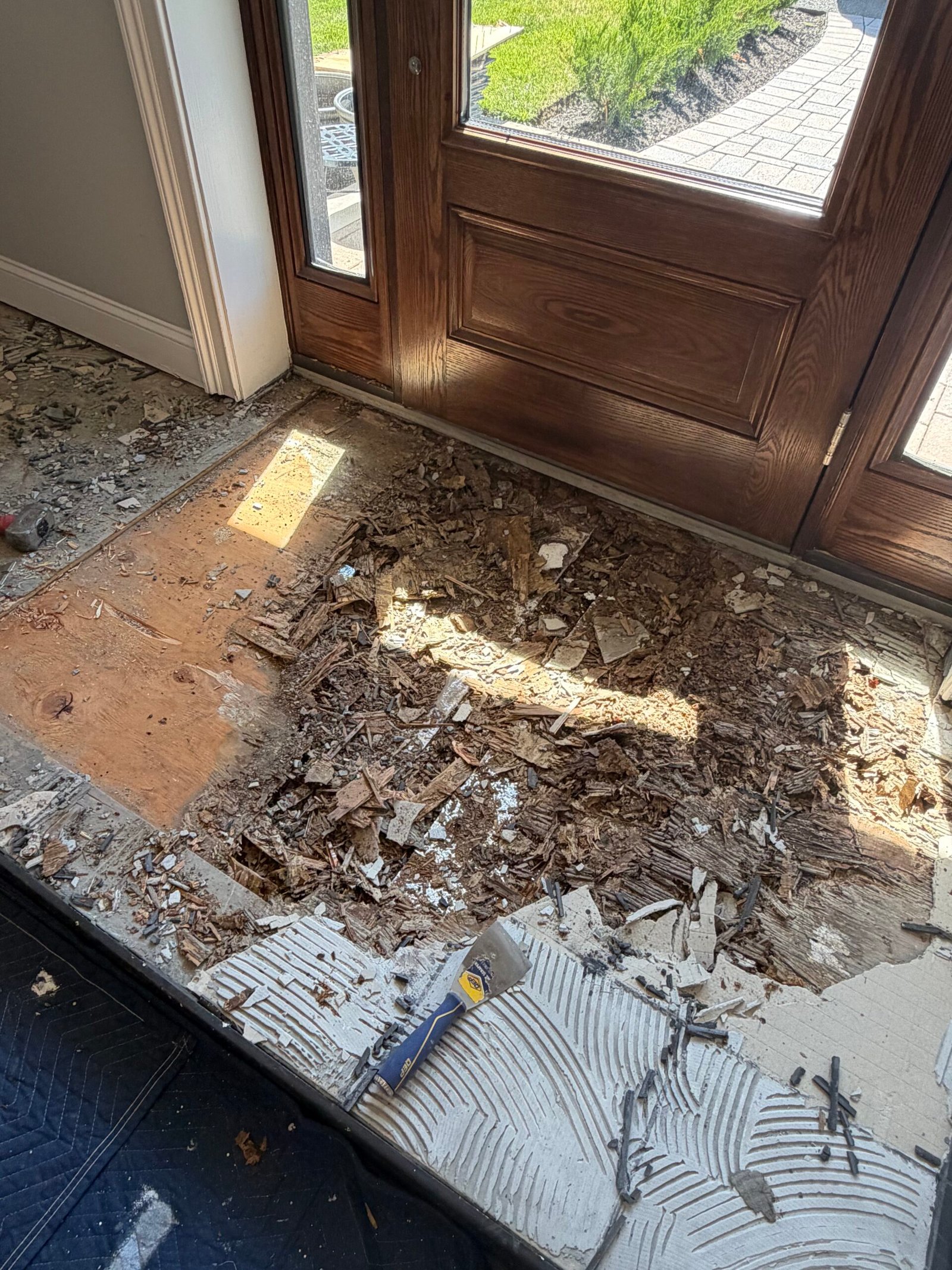The entry floor opened near the front door, with damaged layers being removed.