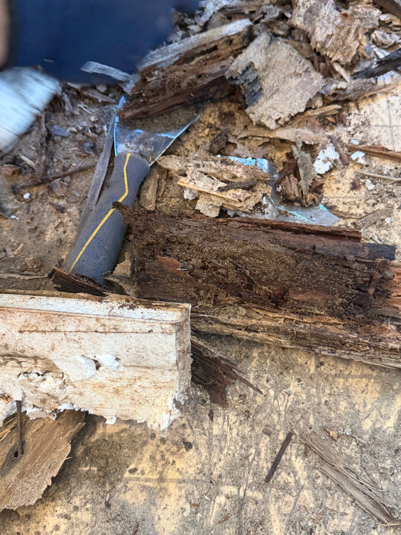 Damaged wood and floor layers visible within the exposed entry area.