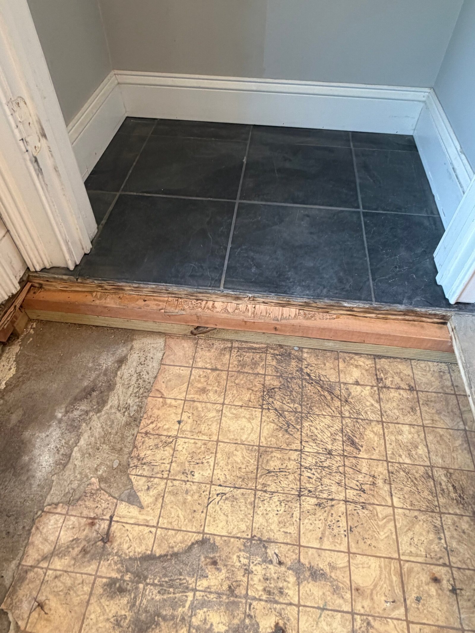 The junction between the cleared entry floor and the retained tiles in the adjoining area.