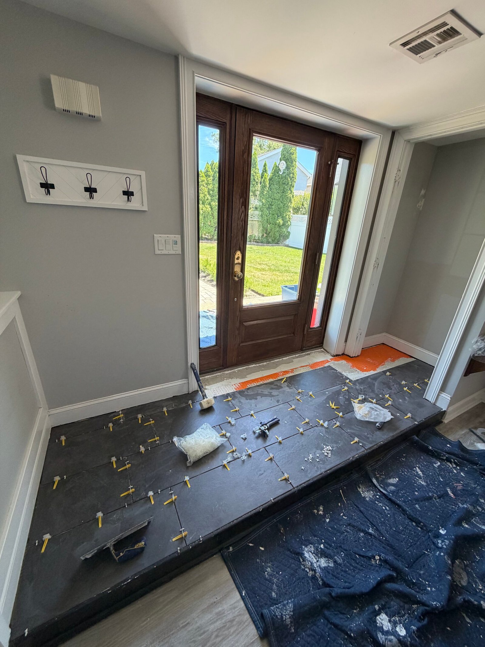 New dark floor tiles during installation, with spacers and leveling clips in place.