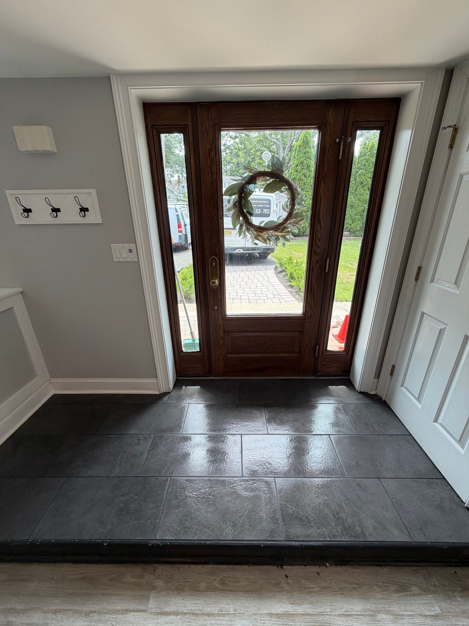 After: the repaired entry floor with completed dark tile, joints and perimeter details.