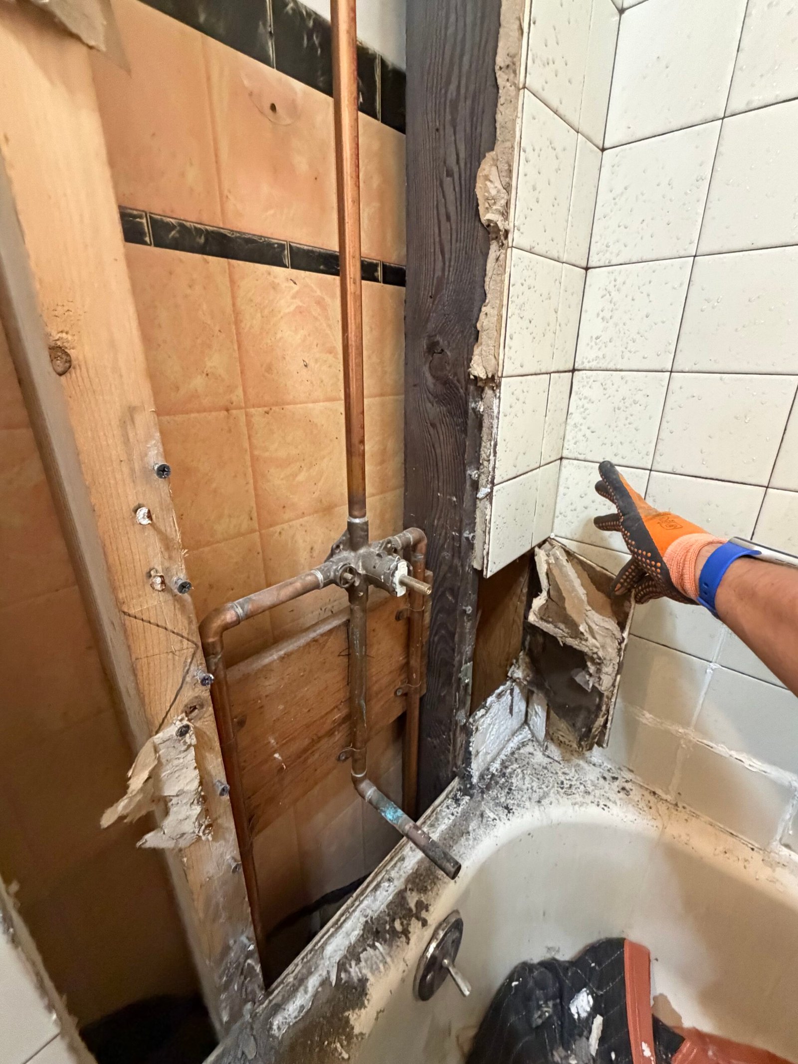Opening the plumbing-side wall and removing the original tile surround.