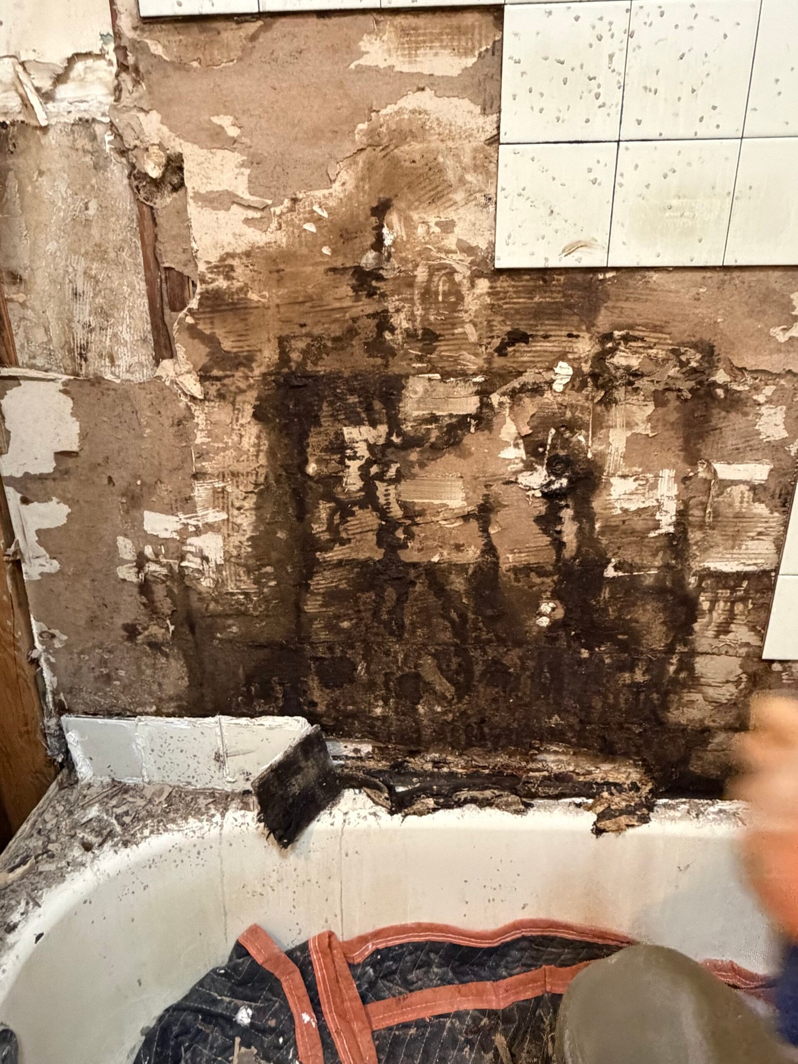 Dark staining and deterioration visible on the exposed wall backing.