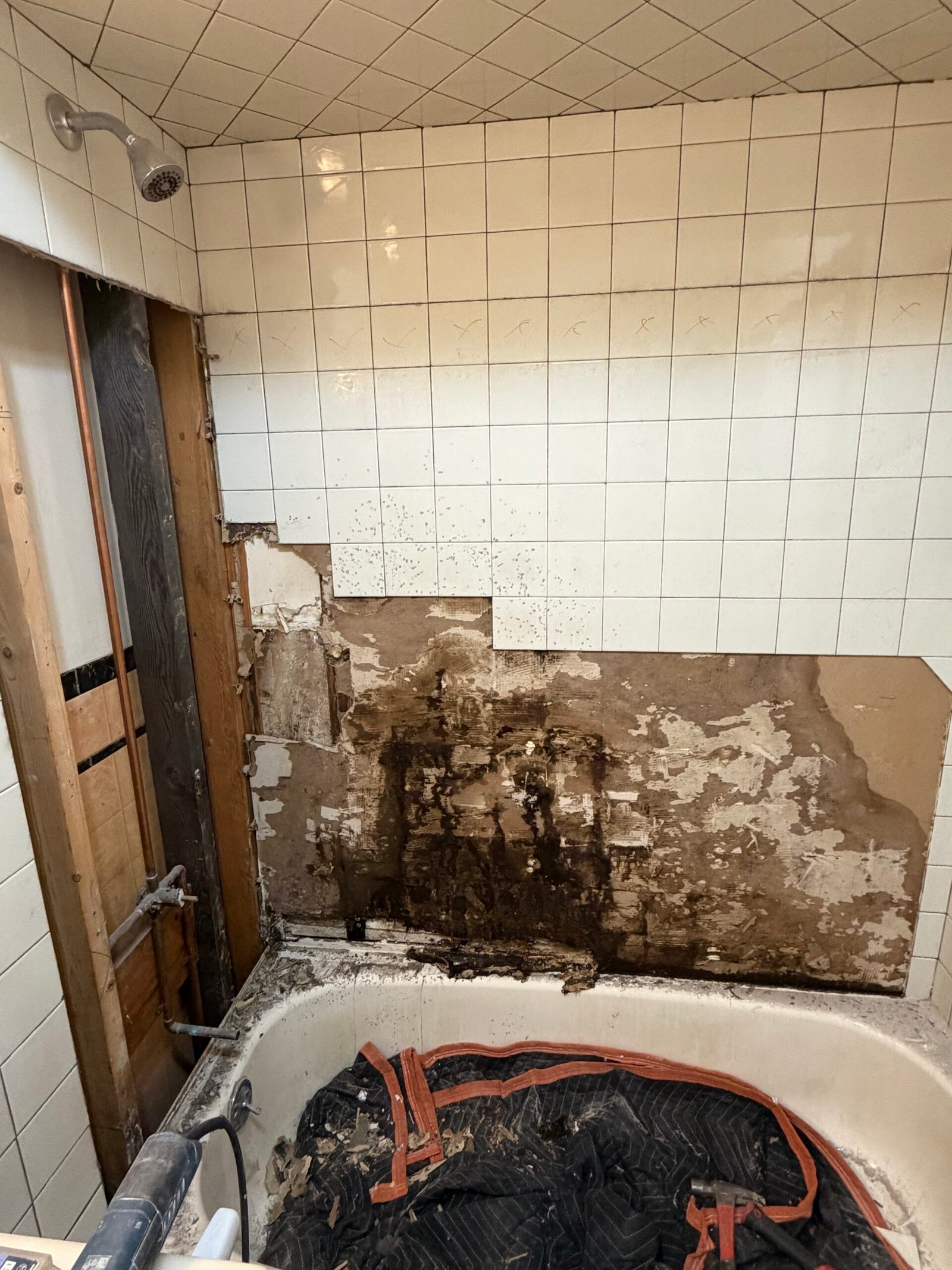 A wider view of the opened tub surround and exposed wall conditions.