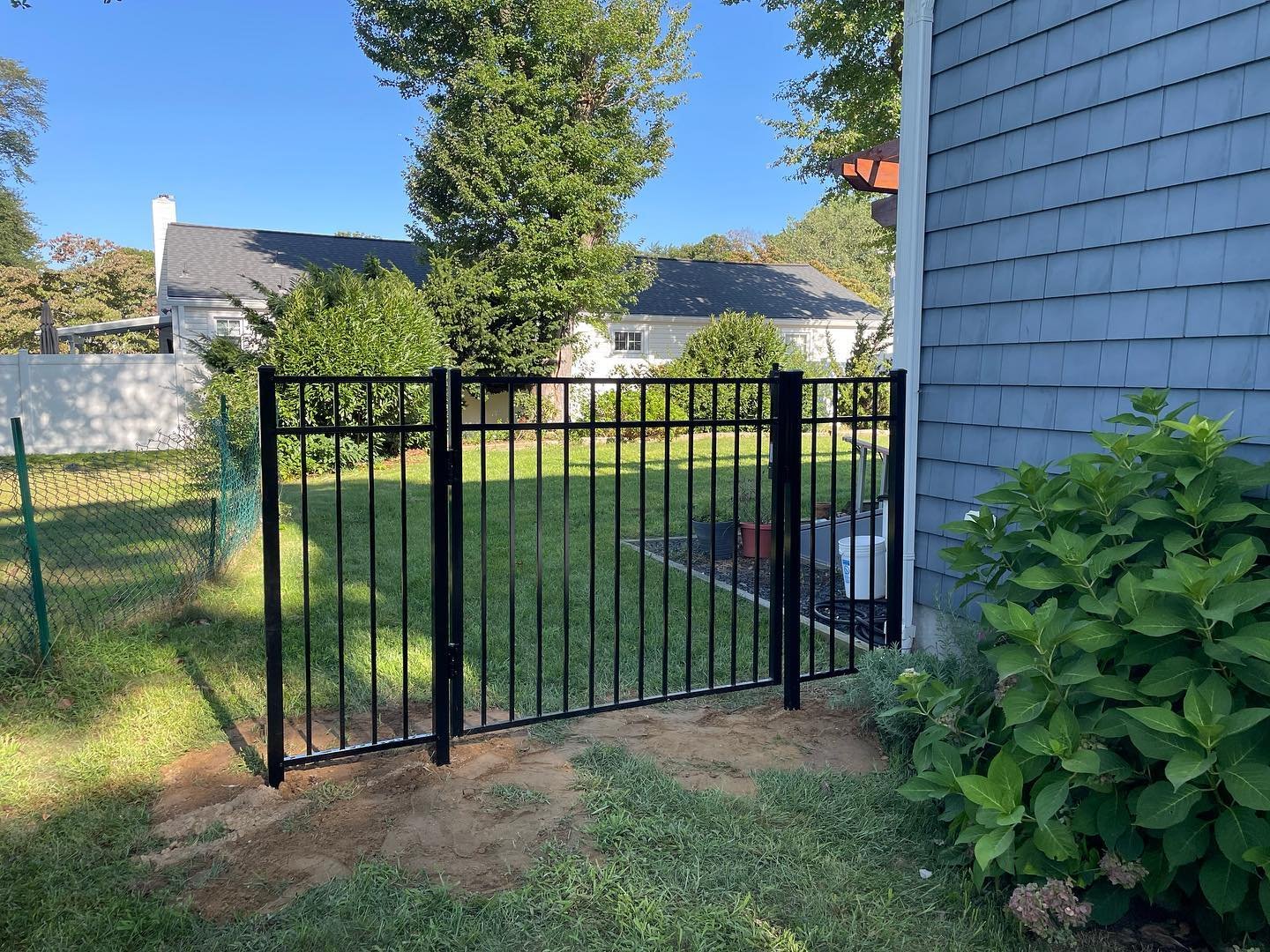 After: the completed black aluminum fence and closed gate across the lawn-side passage.