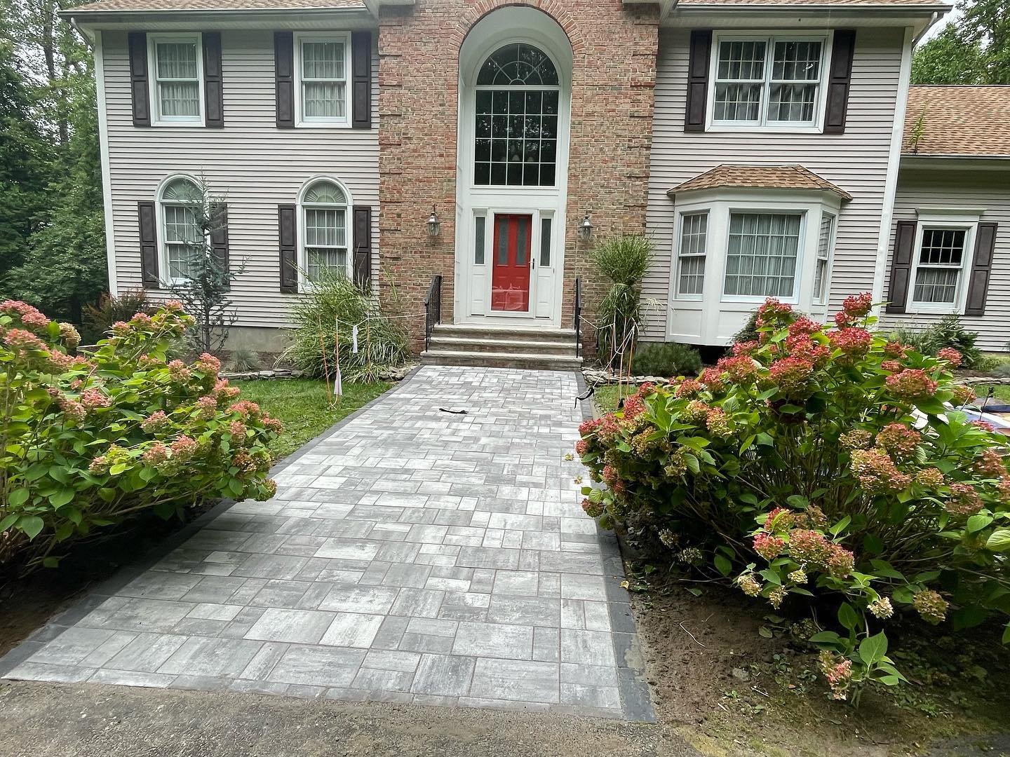 After: the renewed gray paver walkway leading between the garden beds to the front entrance.