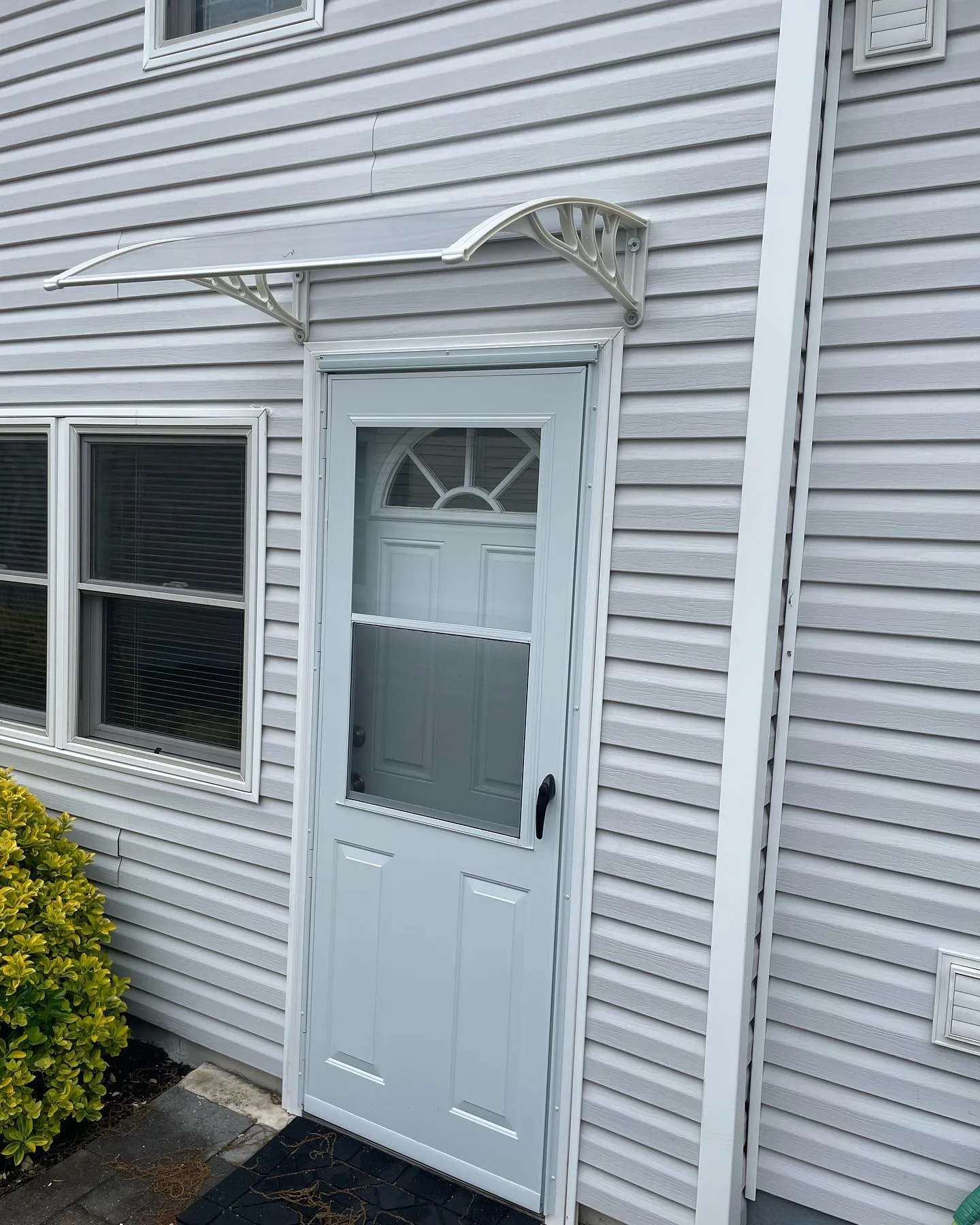 After: the replacement storm door, renewed white molding and entry awning at the light-sided entrance.