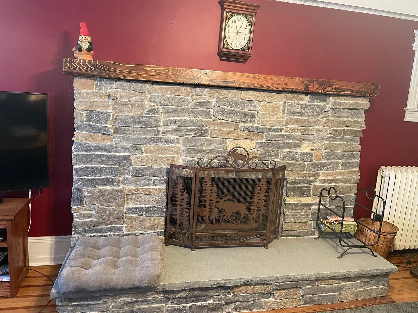 Completed fireplace: natural stone facing, a stone hearth slab and the wood mantel across the top.