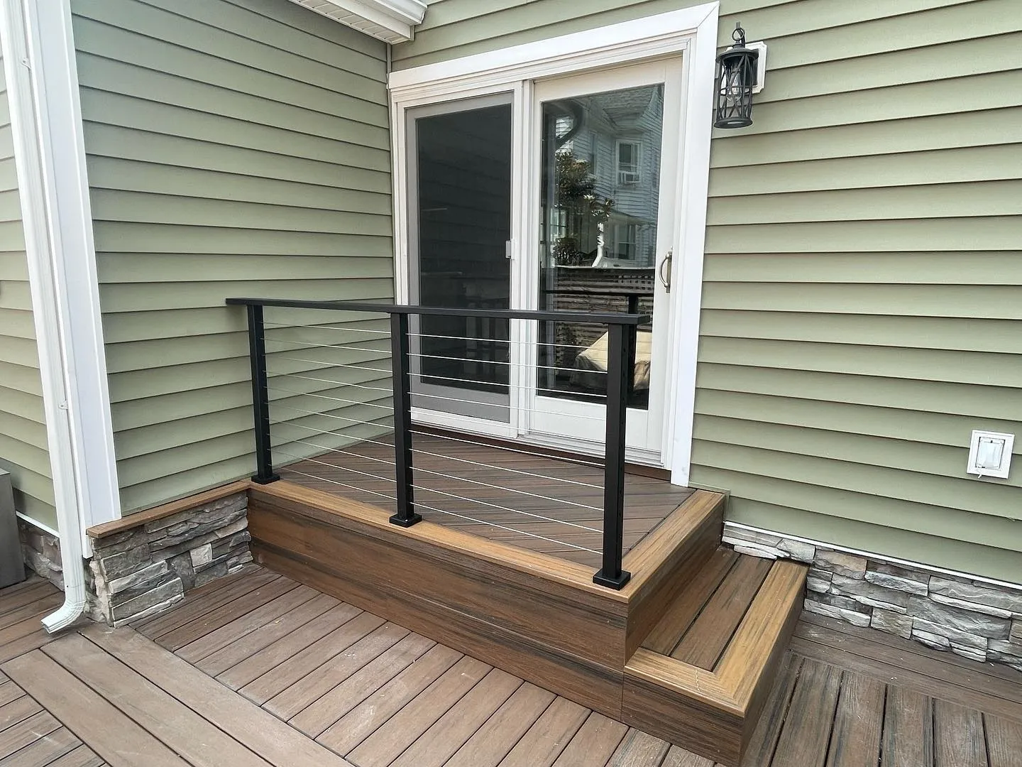 After: the reconstructed landing and steps, black aluminum cable railings and decorative stone facing.