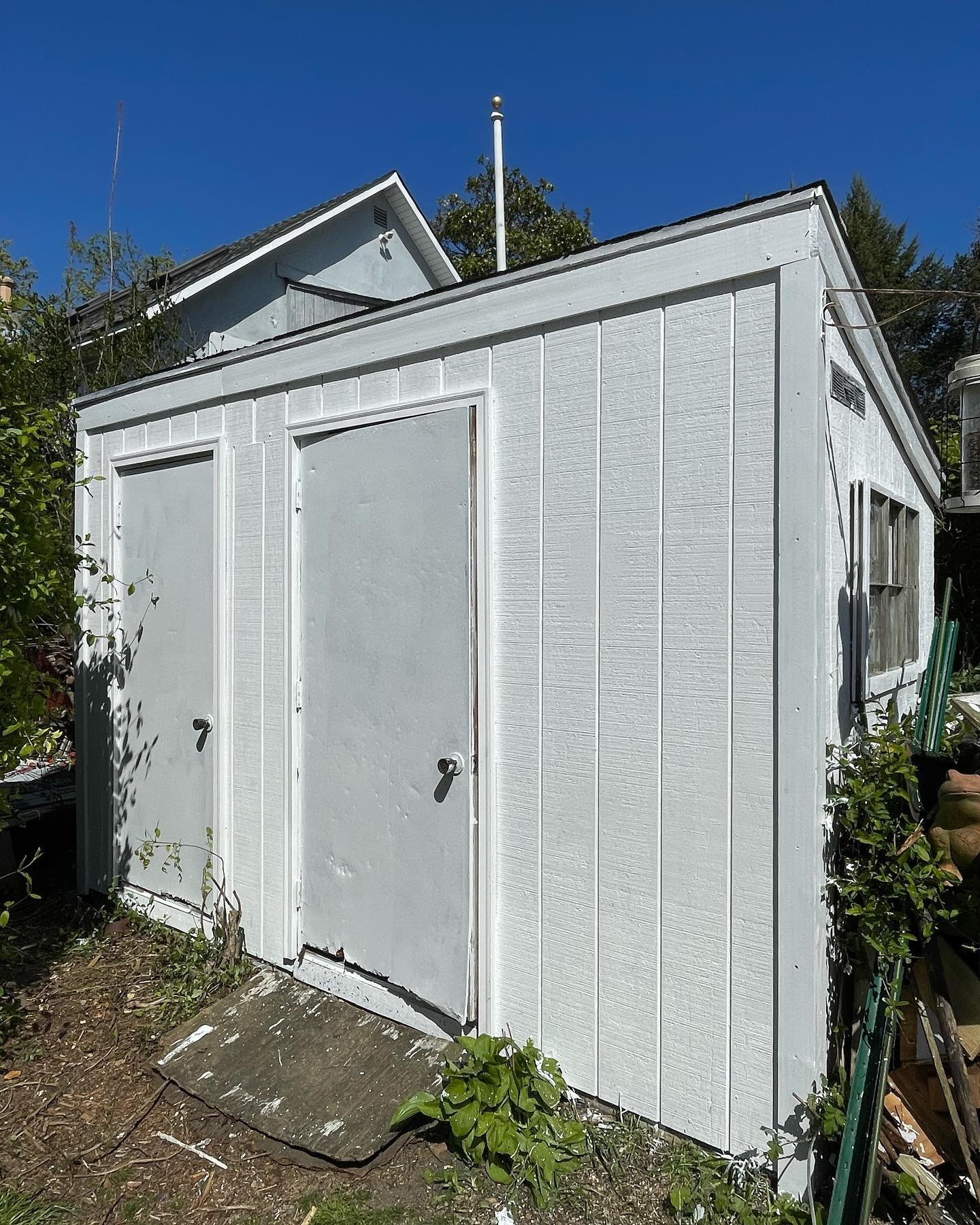 After reconstruction and painting: the renewed shed front with white panels, door faces and trim.