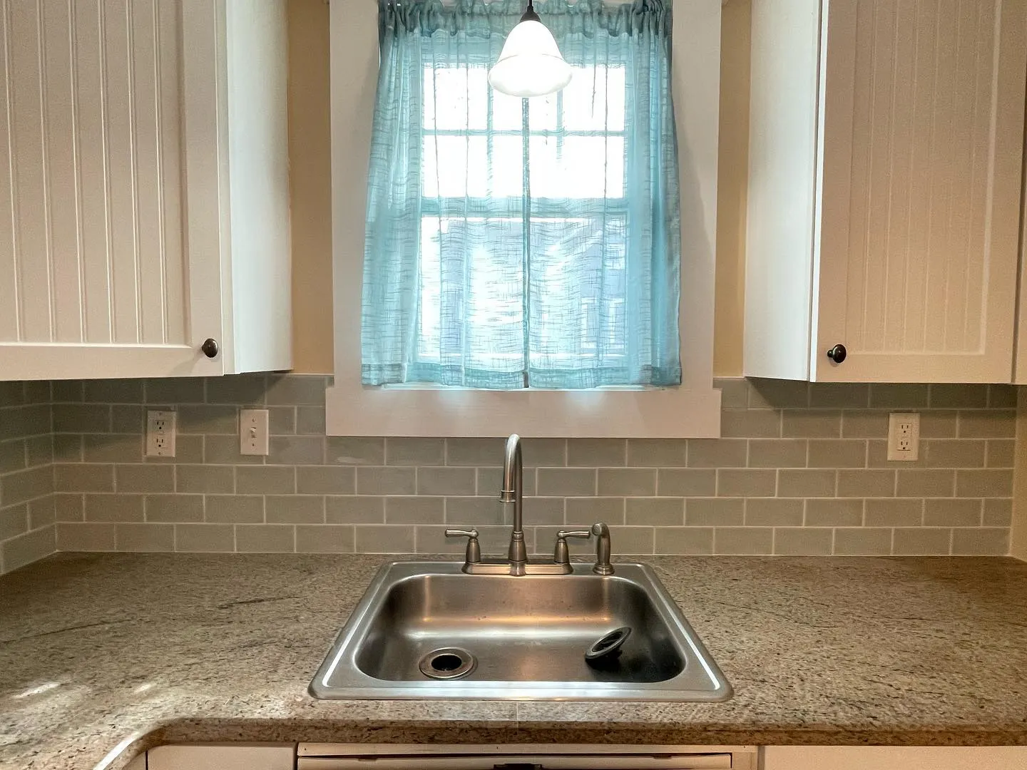 A closer finished view of the tile backsplash around the sink, outlet plates and window trim.