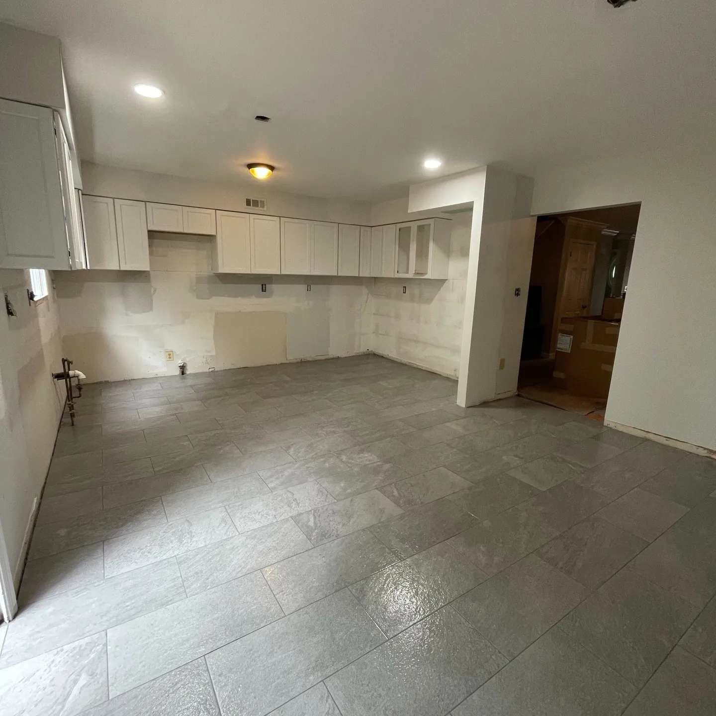 The installed gray rectangular tile floor, shown while the wider kitchen renovation is still in progress.
