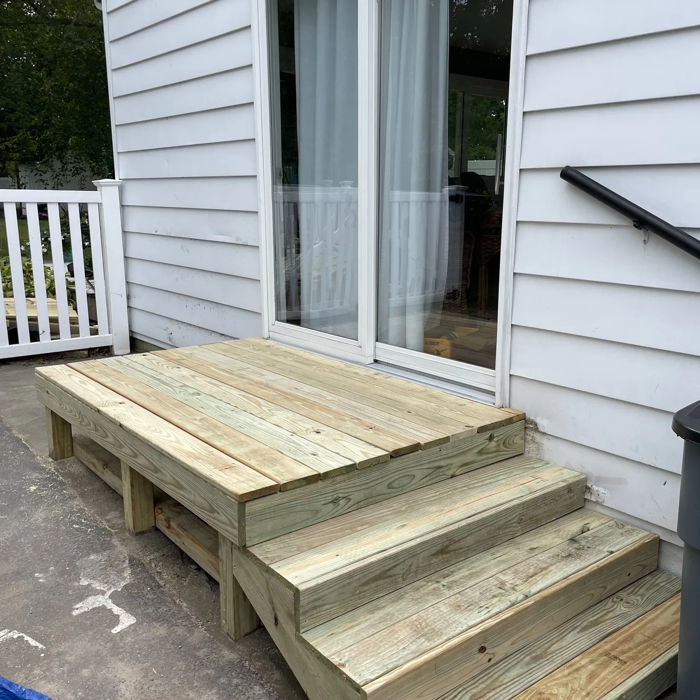 After: the rebuilt timber porch landing and new stair run beneath the sliding door.