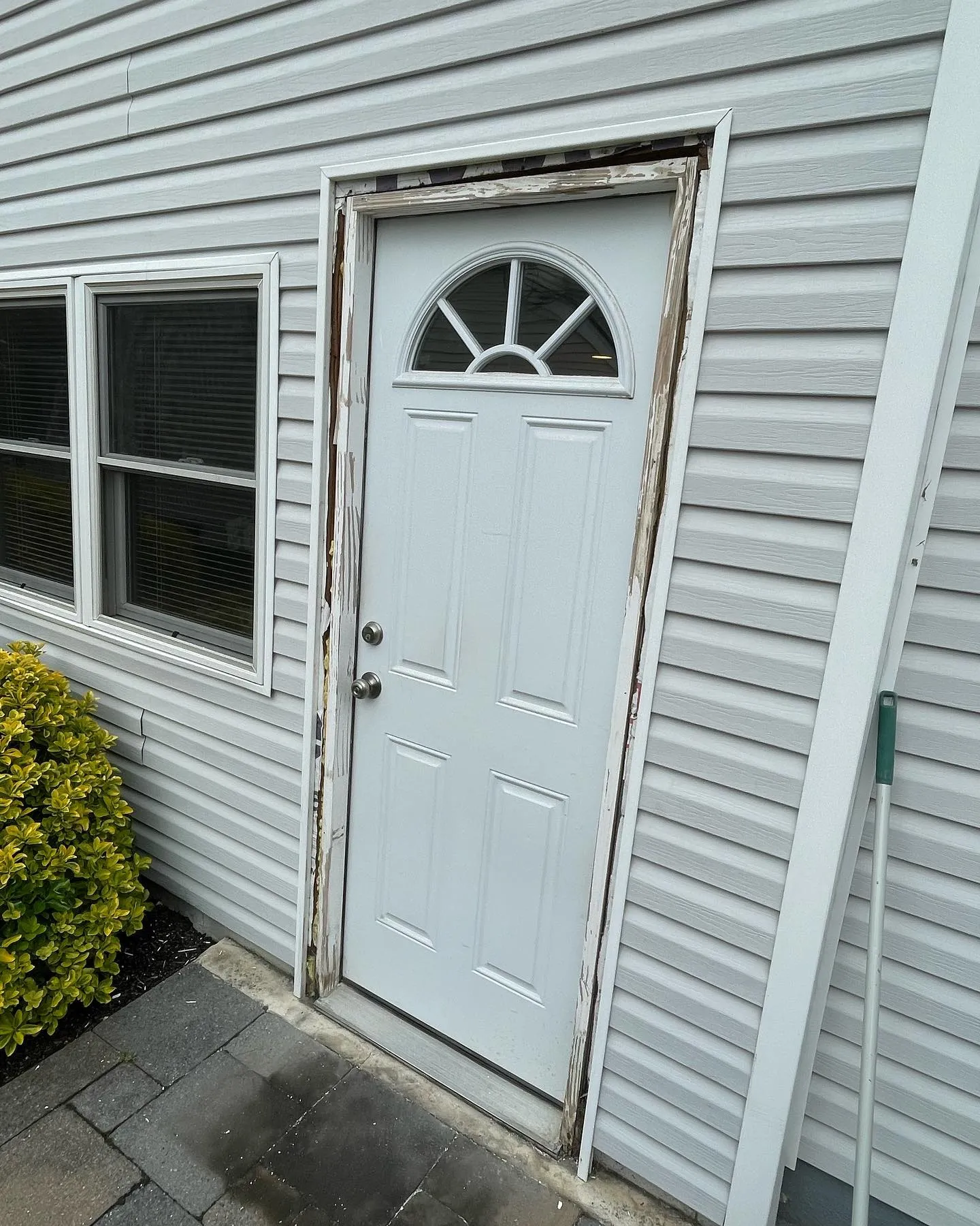 During the work: the storm door has been removed, exposing the existing doorway and upper trim area.