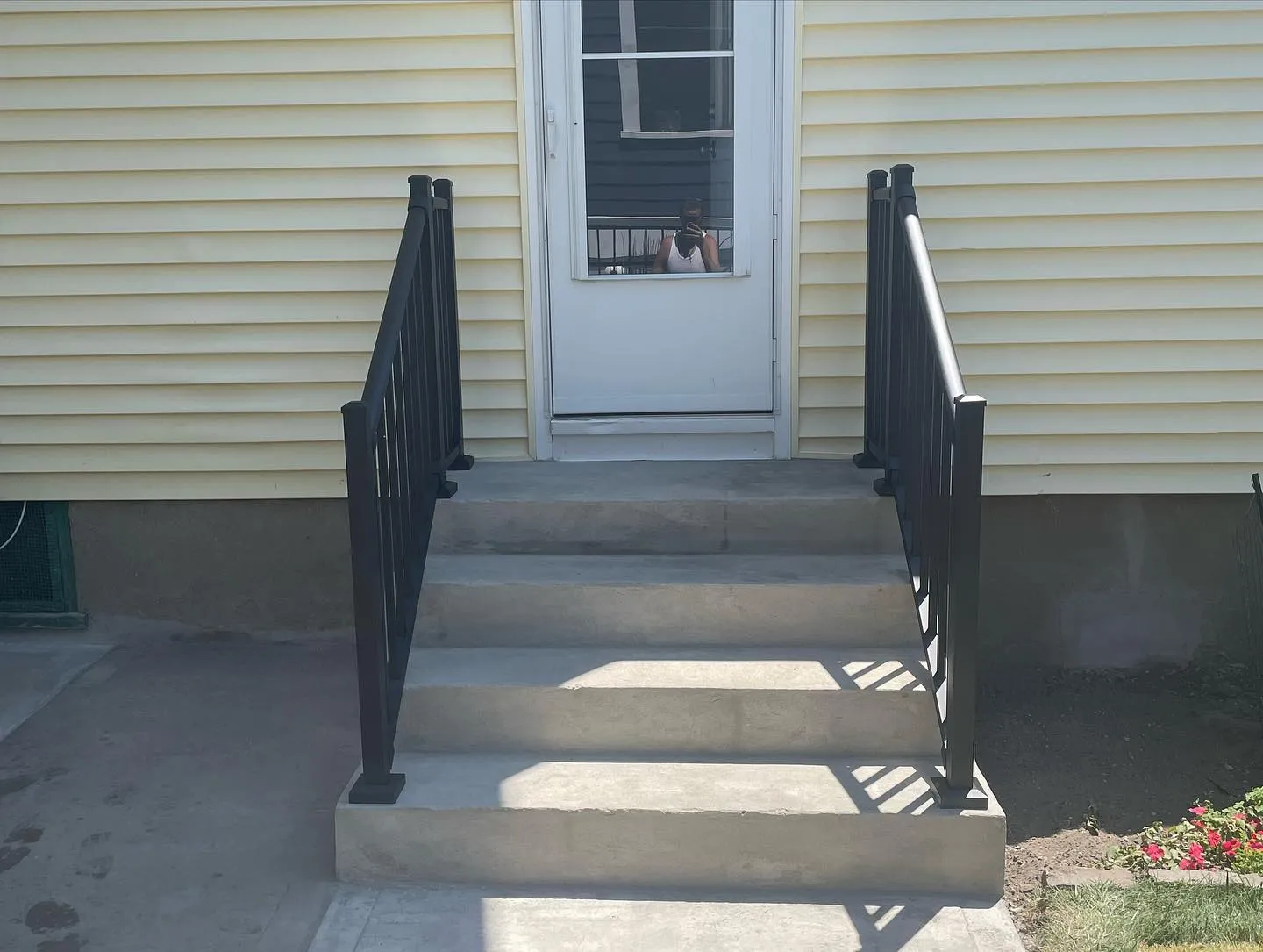 After: completed concrete steps with black aluminum railings on both sides.