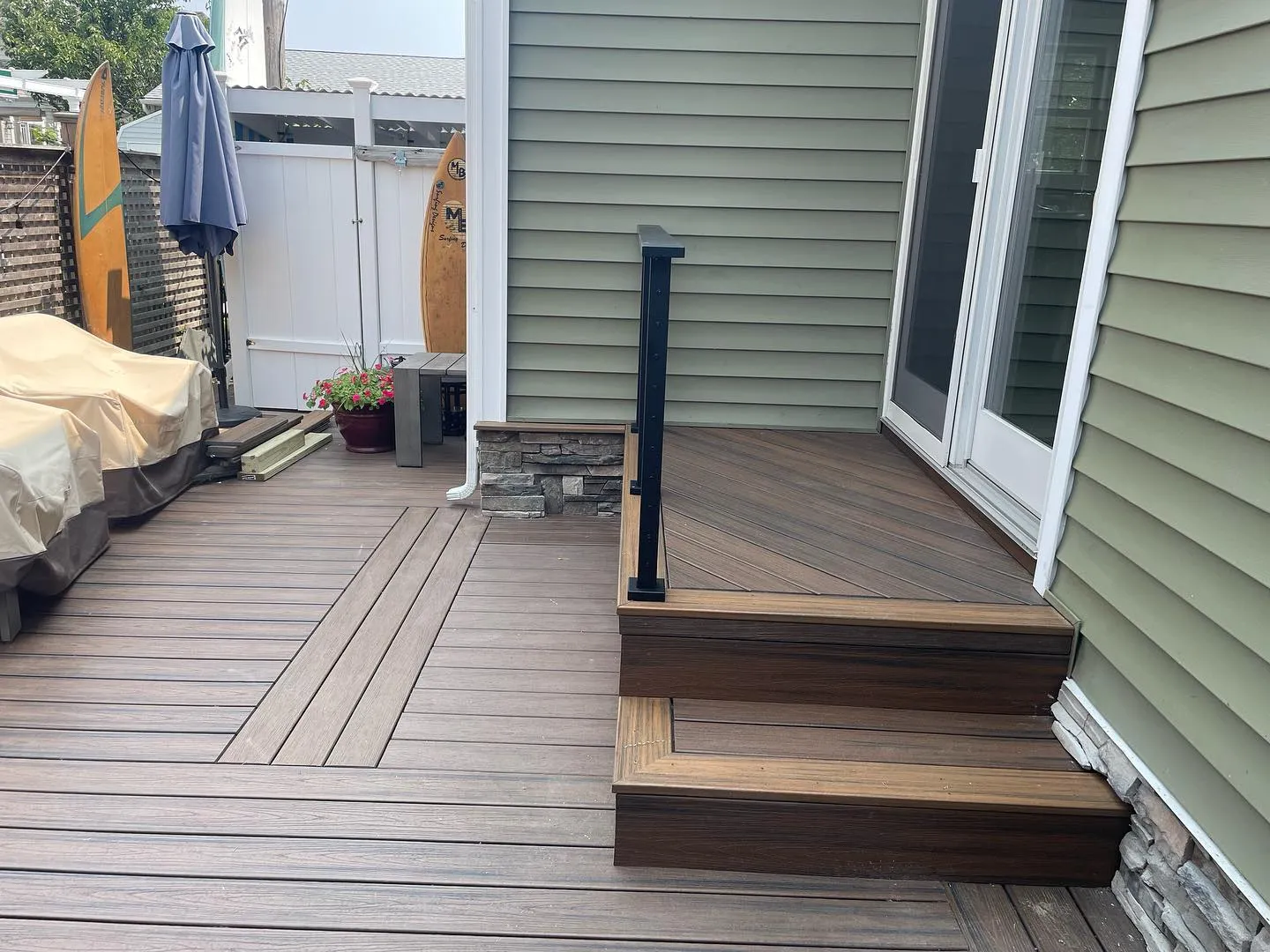 Side view of the finished deck-board landing, stair treads and decorative stone along the wall base.