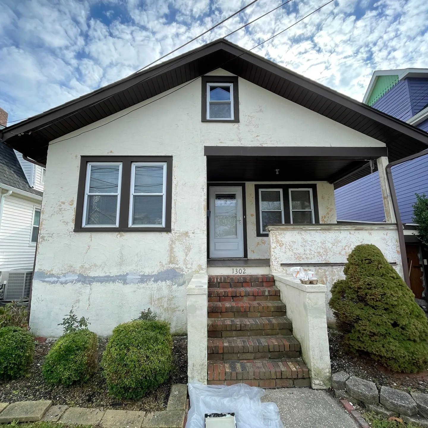 Before repainting: the exterior wall with a worn, patchy finish and visible surface repair areas.