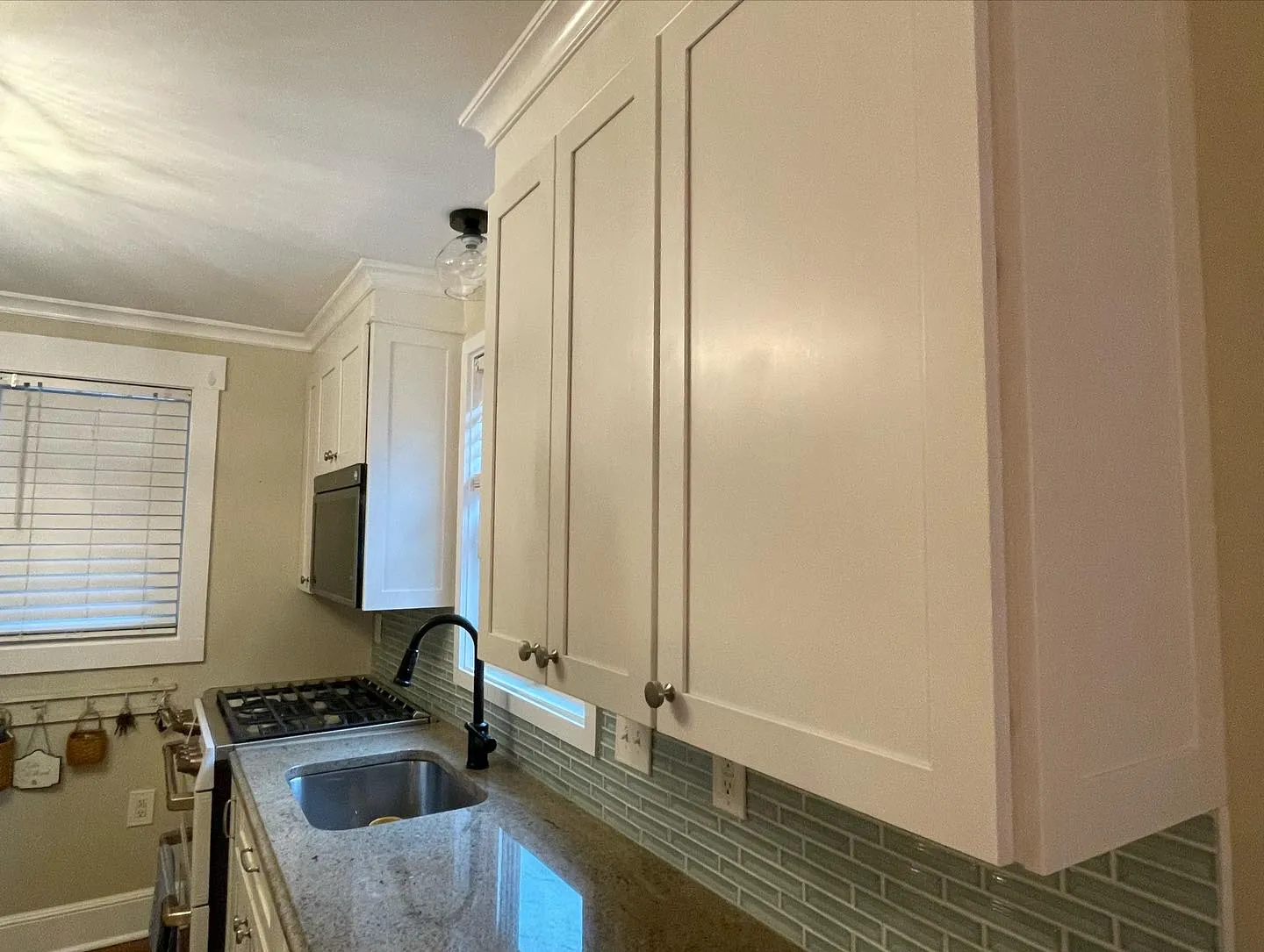 The finished white cabinet fronts and rectangular backsplash along the sink and adjoining counter.