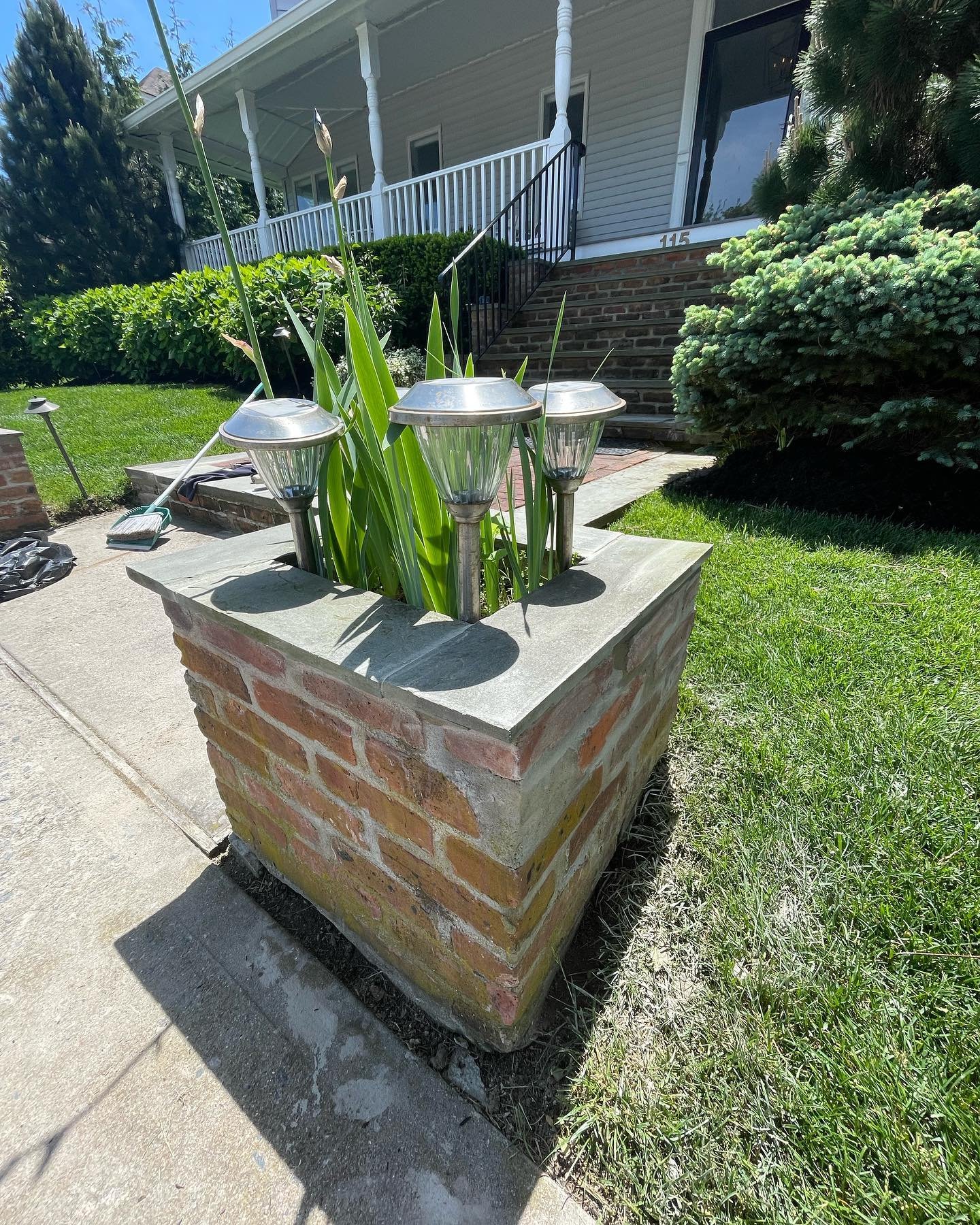 Installed stone cap sections forming a continuous gray border above the existing brick pillar.