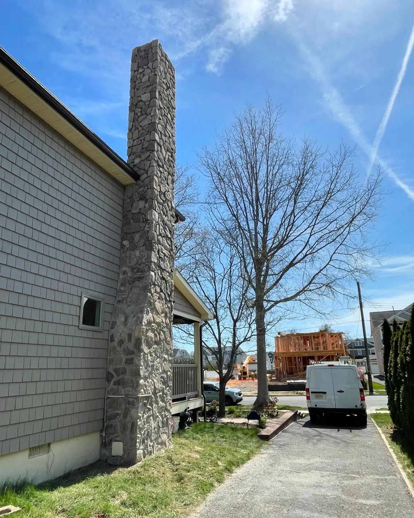 After: stone cladding continuing from the base to the top of the chimney, viewed along the driveway.