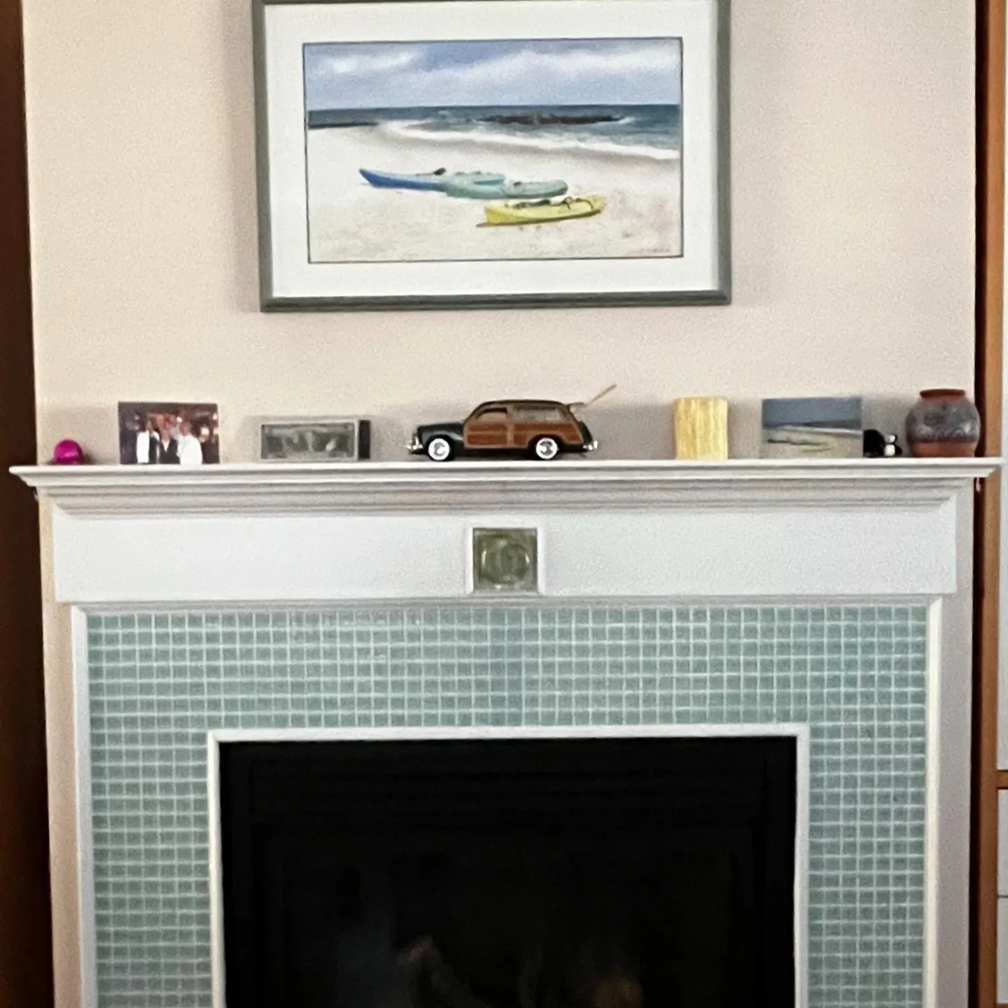 Before: the small mosaic-tile fireplace surround and white-painted wood mantel and trim.