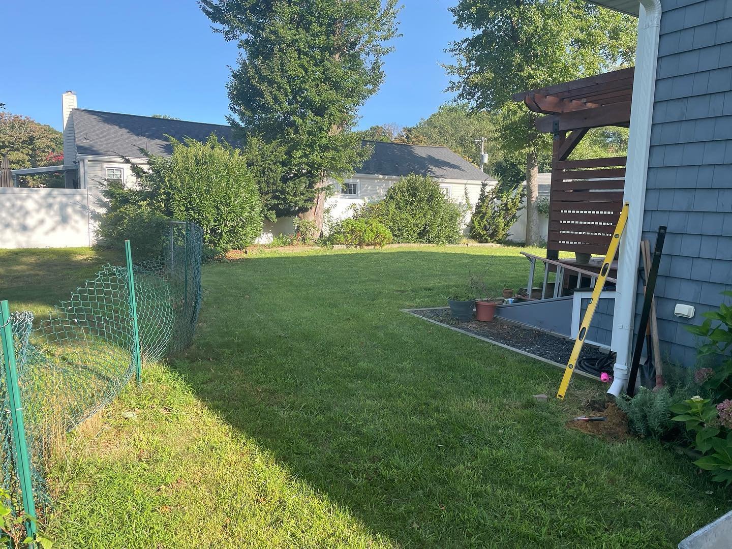 Before: the open lawn-side passage beside the house and existing wire fence.