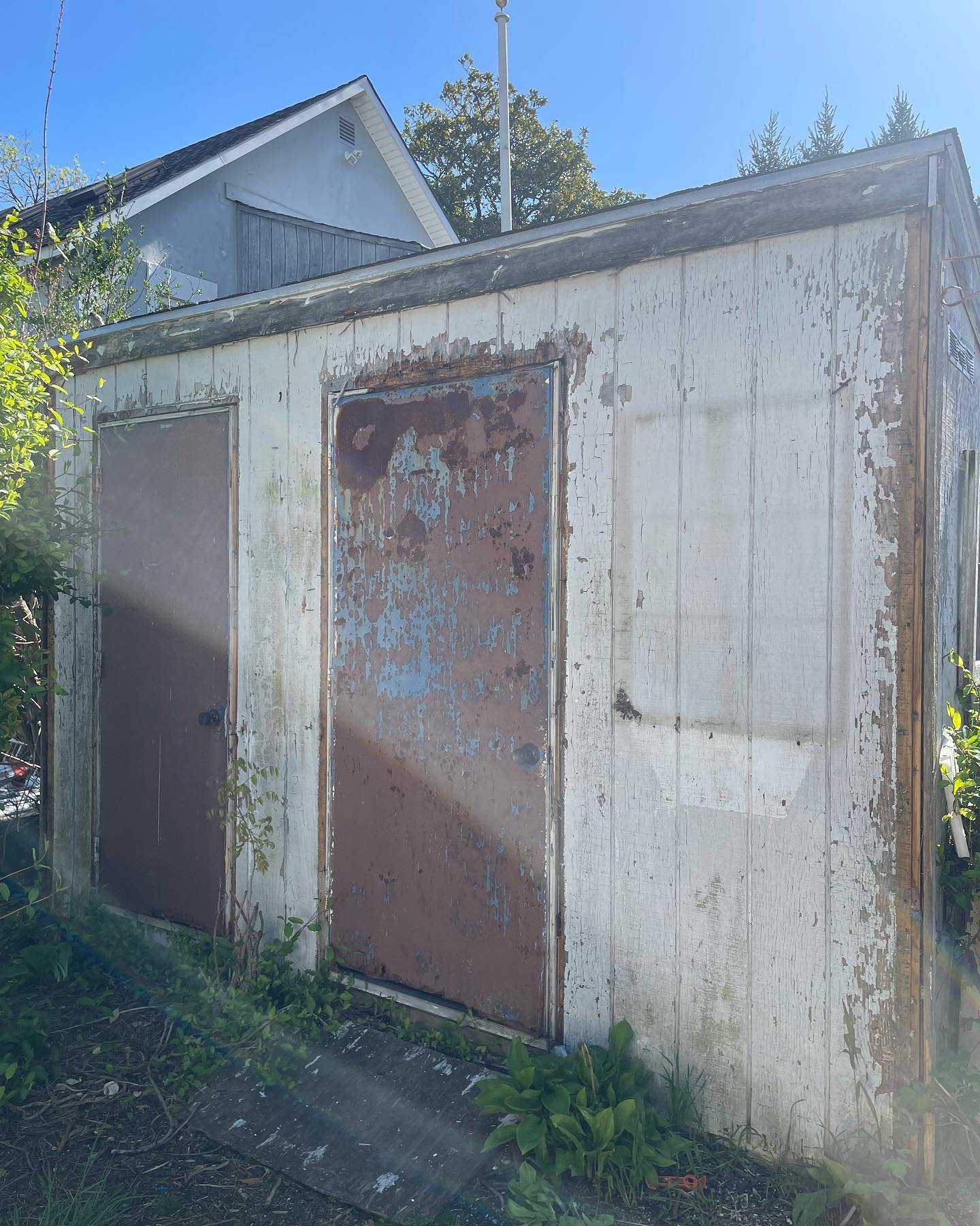 Before: the storage shed with worn front panels, peeling paint and weathered door faces.