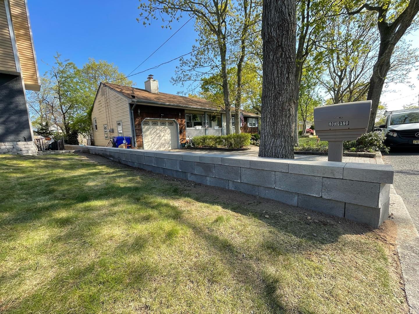 After: the lawn-facing side of the rebuilt wall, with finished caps beside the tree and mailbox.