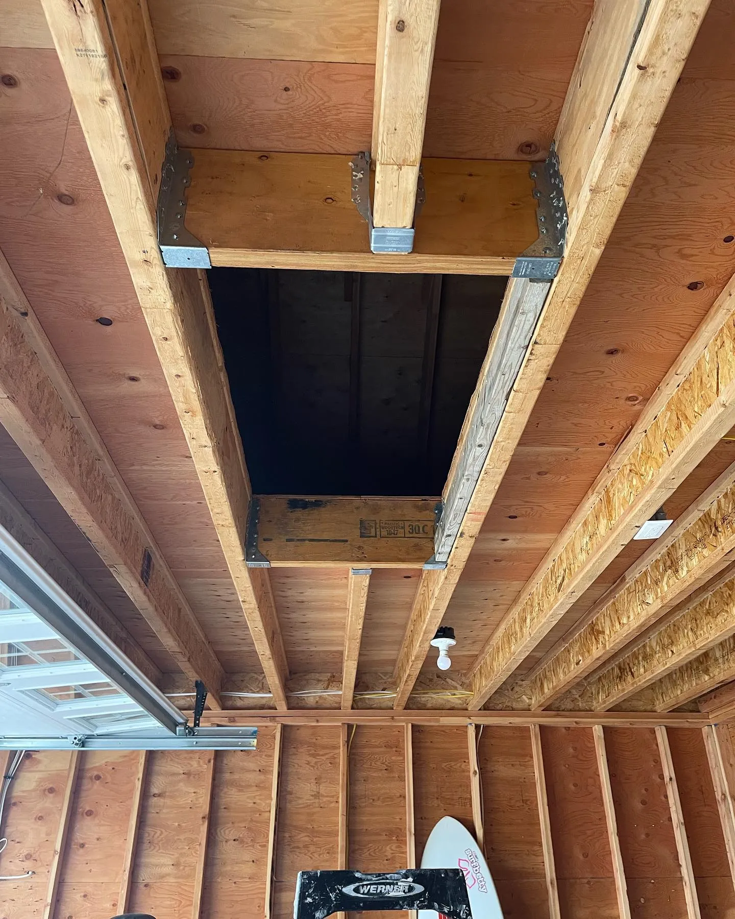Before installation: the open attic access within the exposed garage ceiling framing.