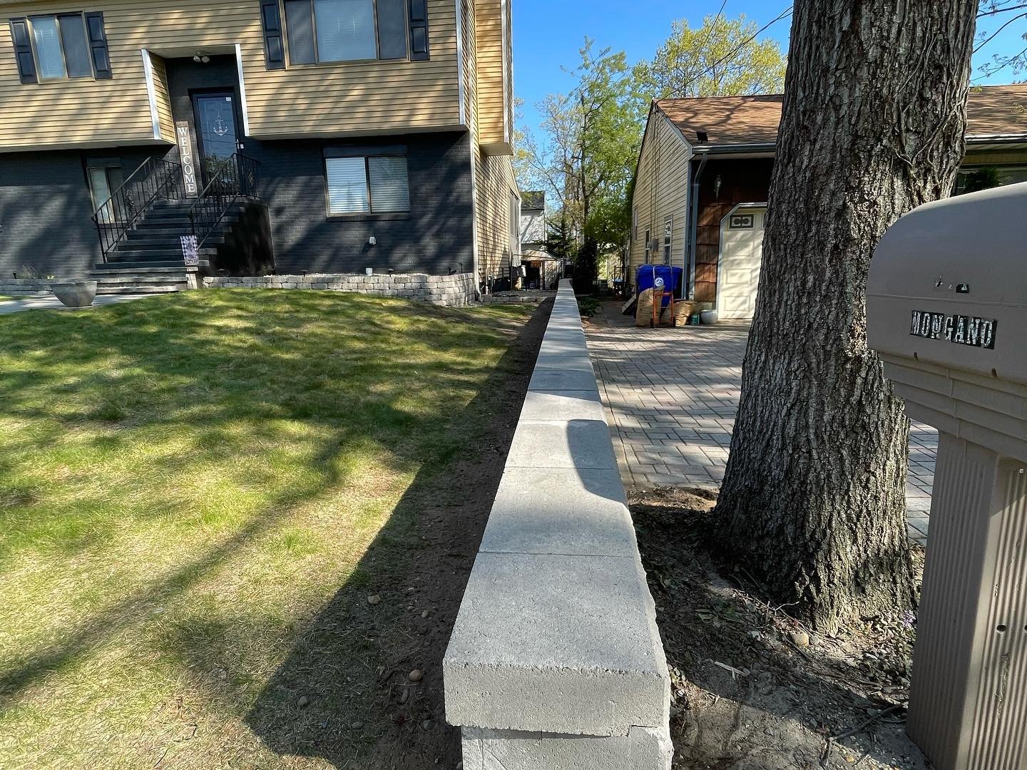 The completed cap line between the lawn and paved approach, viewed toward the house and side gate.