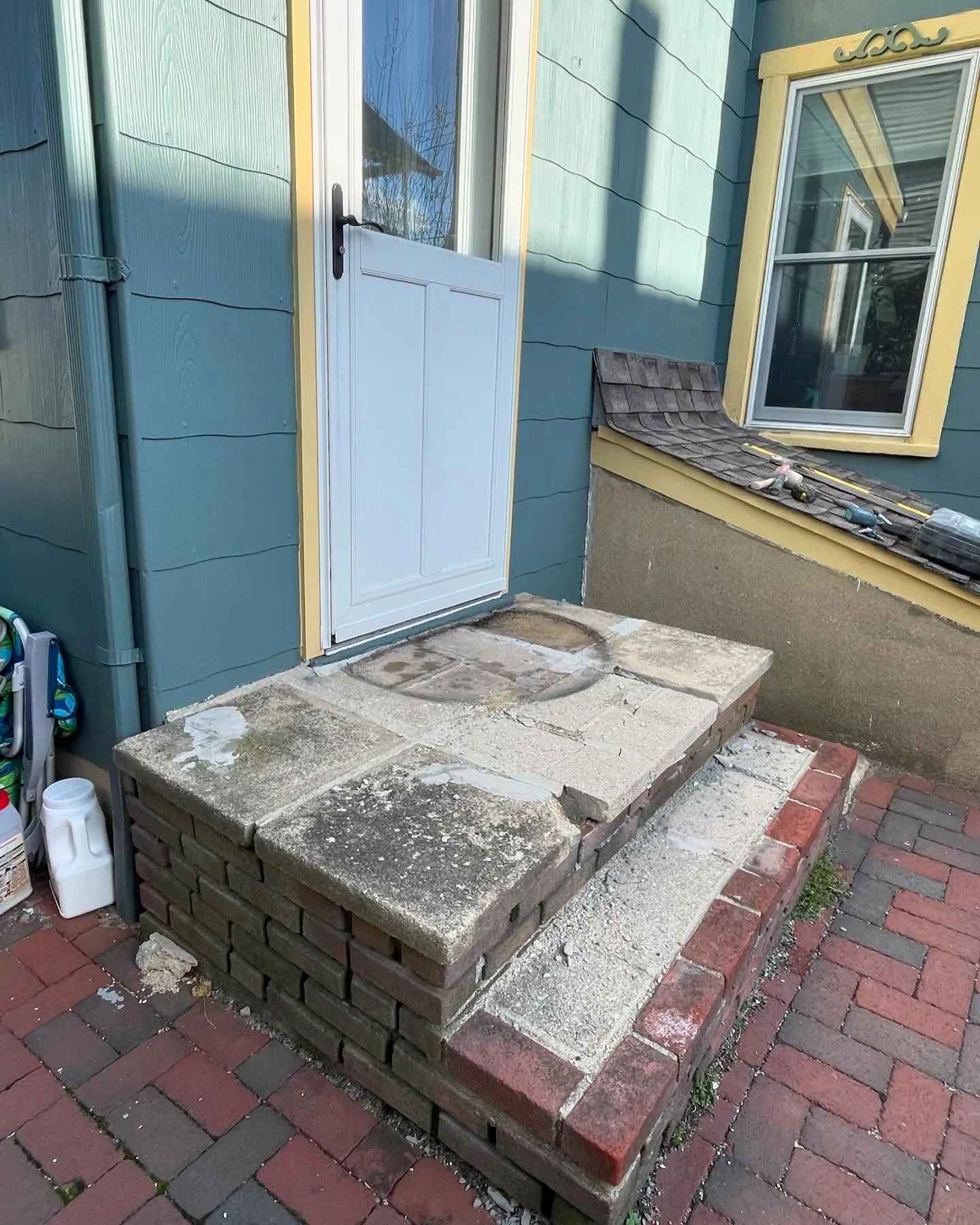 Before: a side view of the old landing slabs, lower tread and exposed brick side face.
