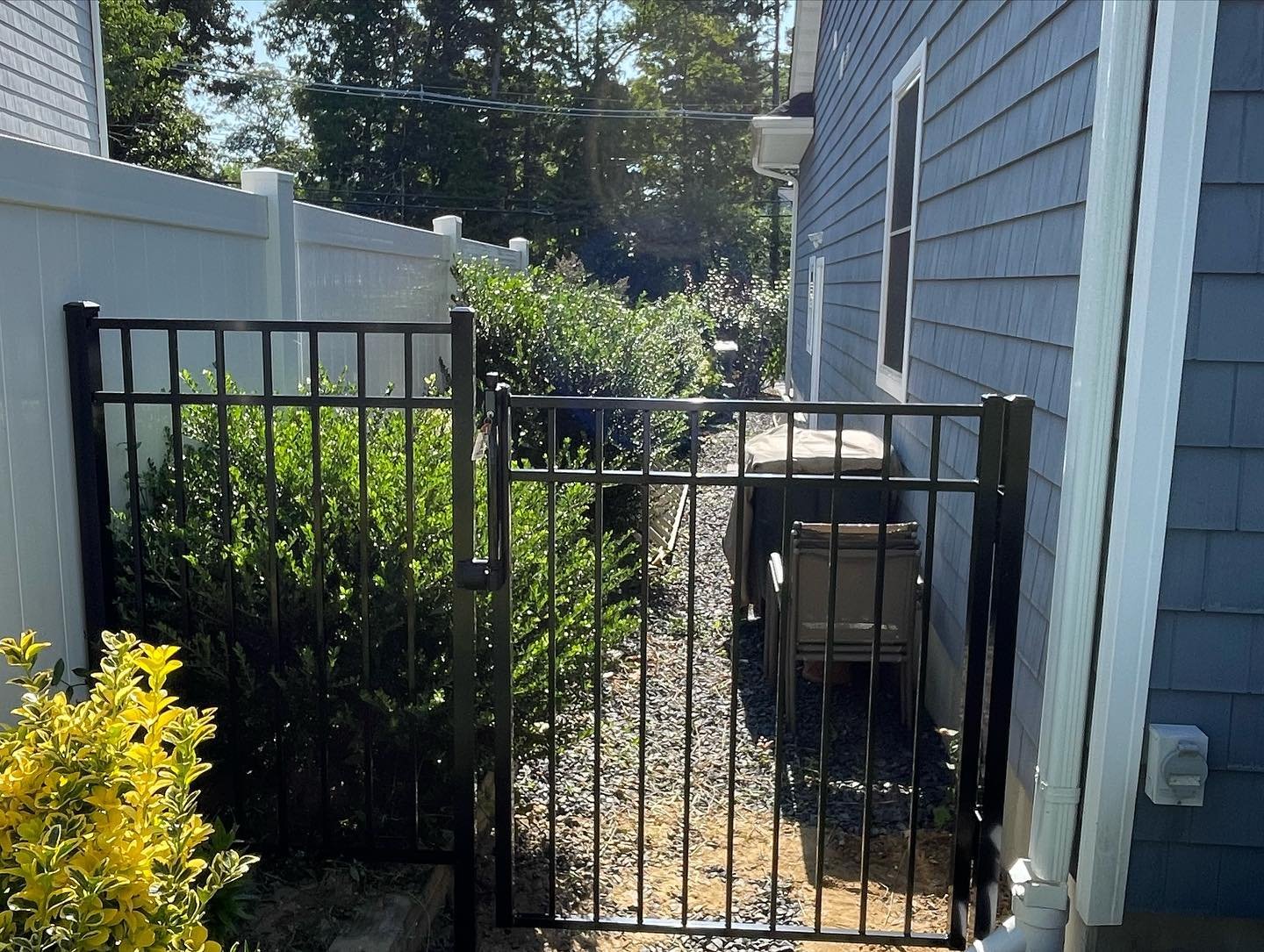 After: the completed aluminum fence and gate between the house and the existing white boundary fence.