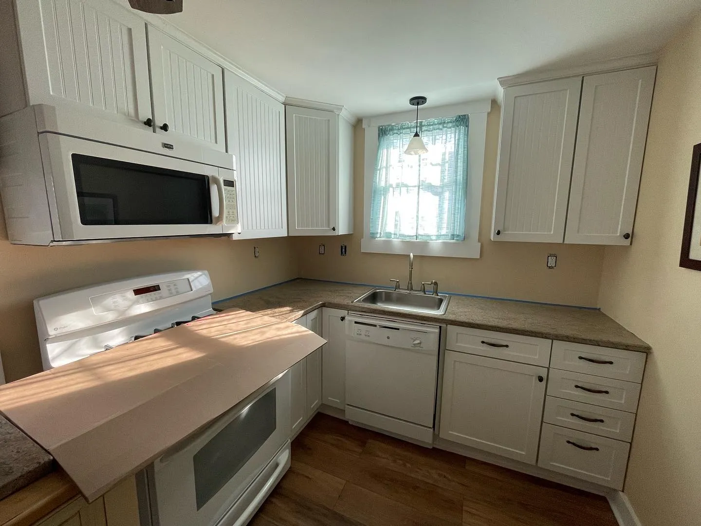 Before: the kitchen with a pink wall finish between the white cabinets and countertop.
