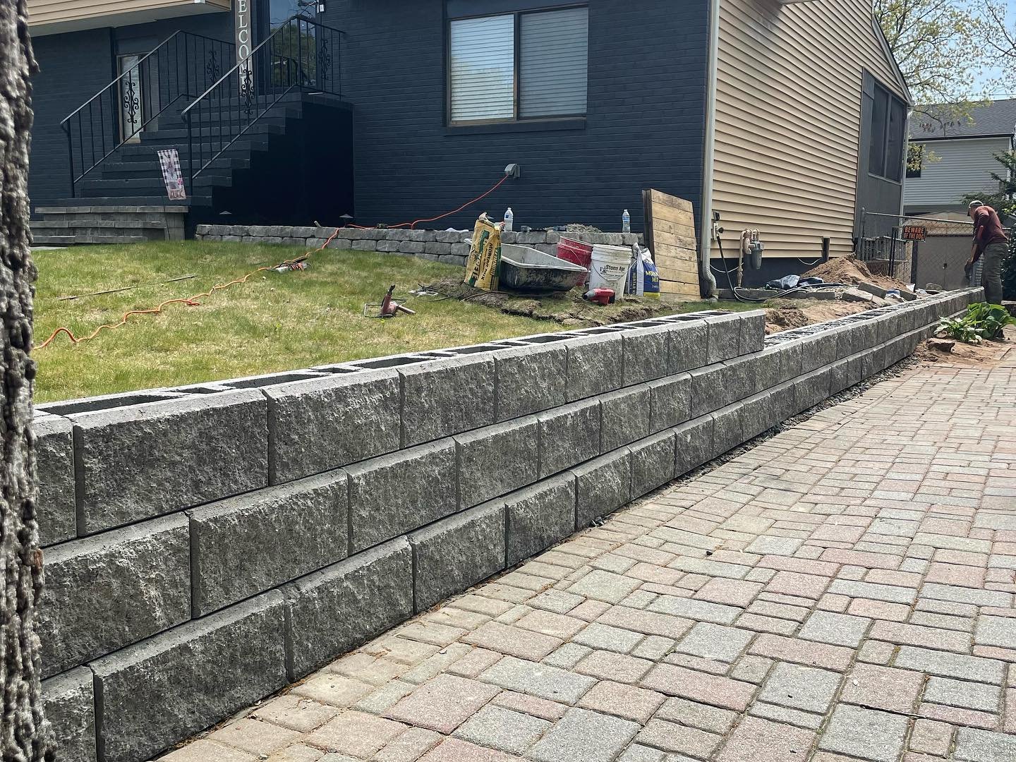 The new gray block wall during construction, with staggered courses and open block cores before the caps.