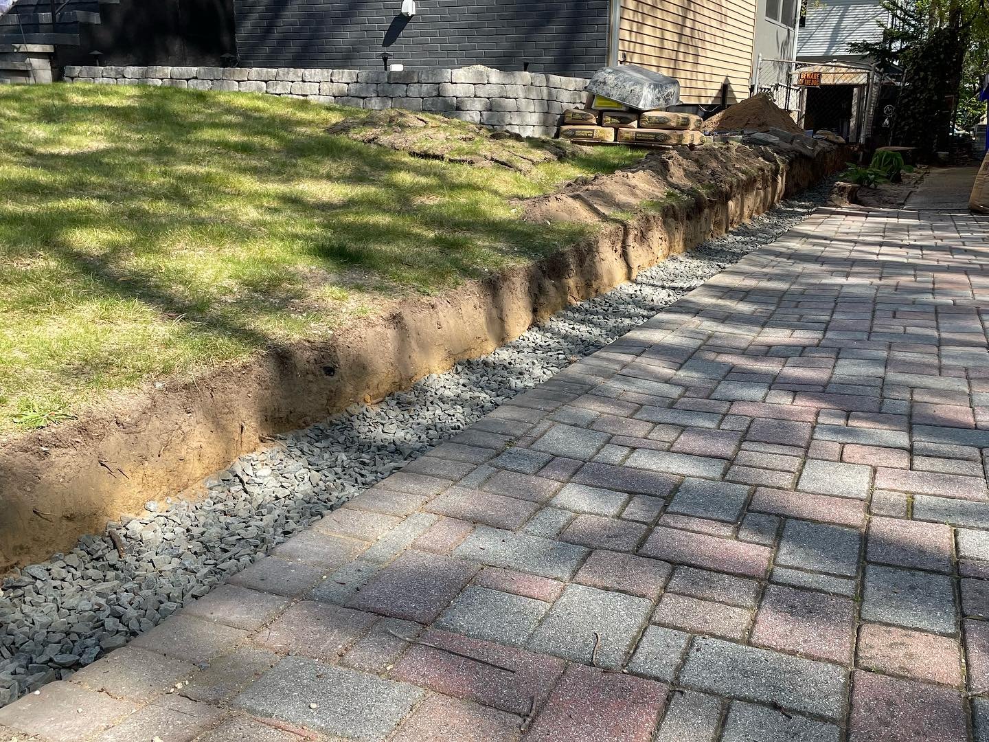 Crushed stone placed in the wall trench beside the existing pavers before the block courses were built.