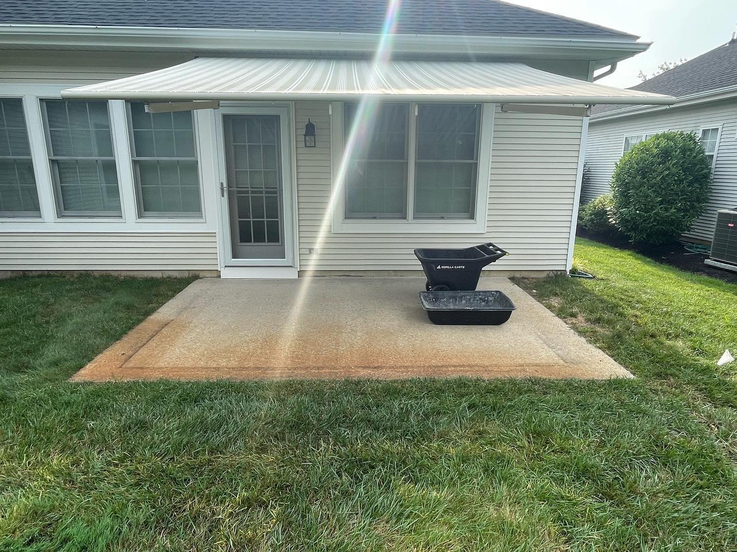Before: the original concrete patio outside the rear door, surrounded by lawn.