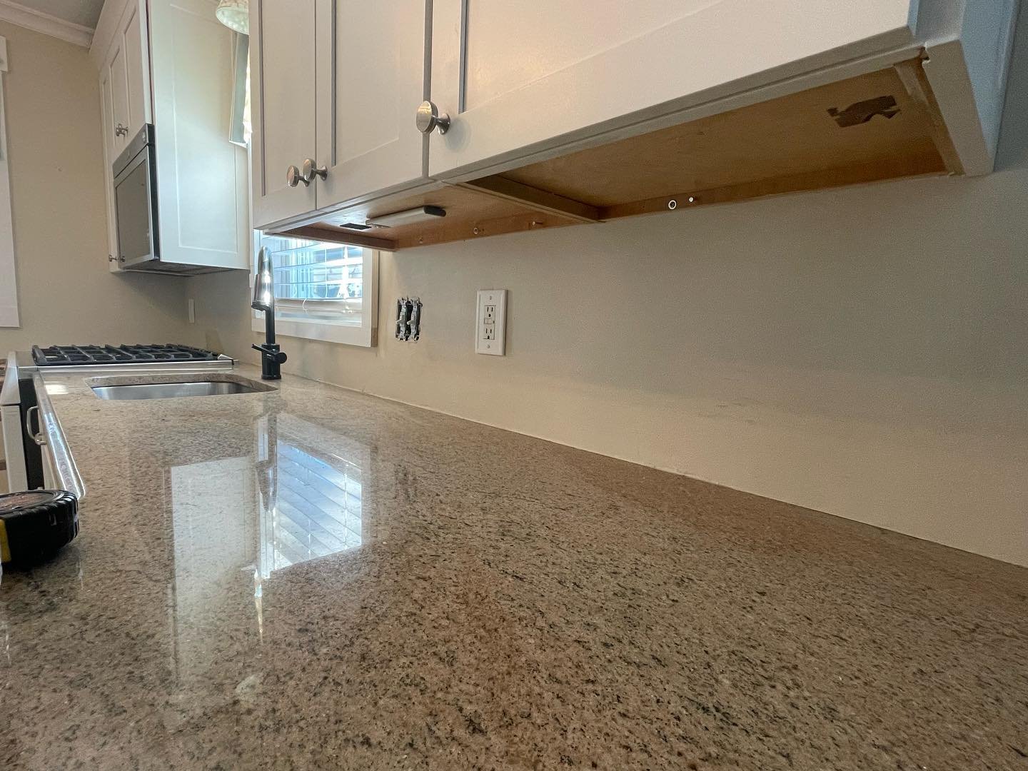 The wall beneath the upper cabinets before the new backsplash, with the countertop and outlet openings visible.