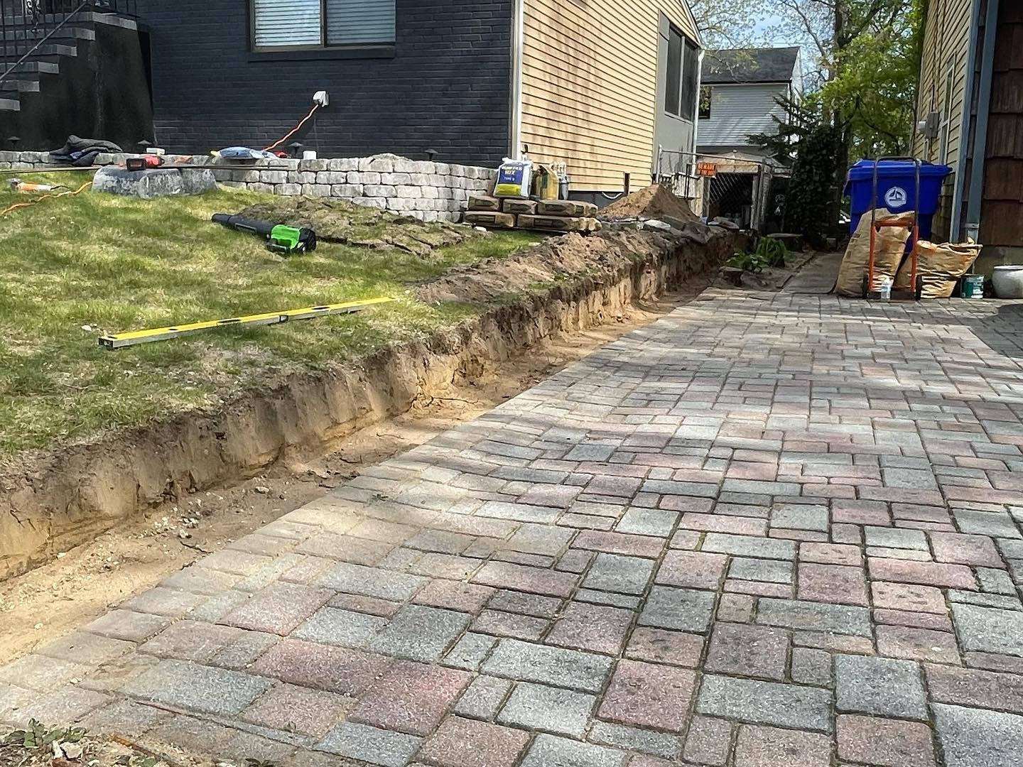 During removal: the old retaining wall taken out, exposing the soil edge beside the retained paving.