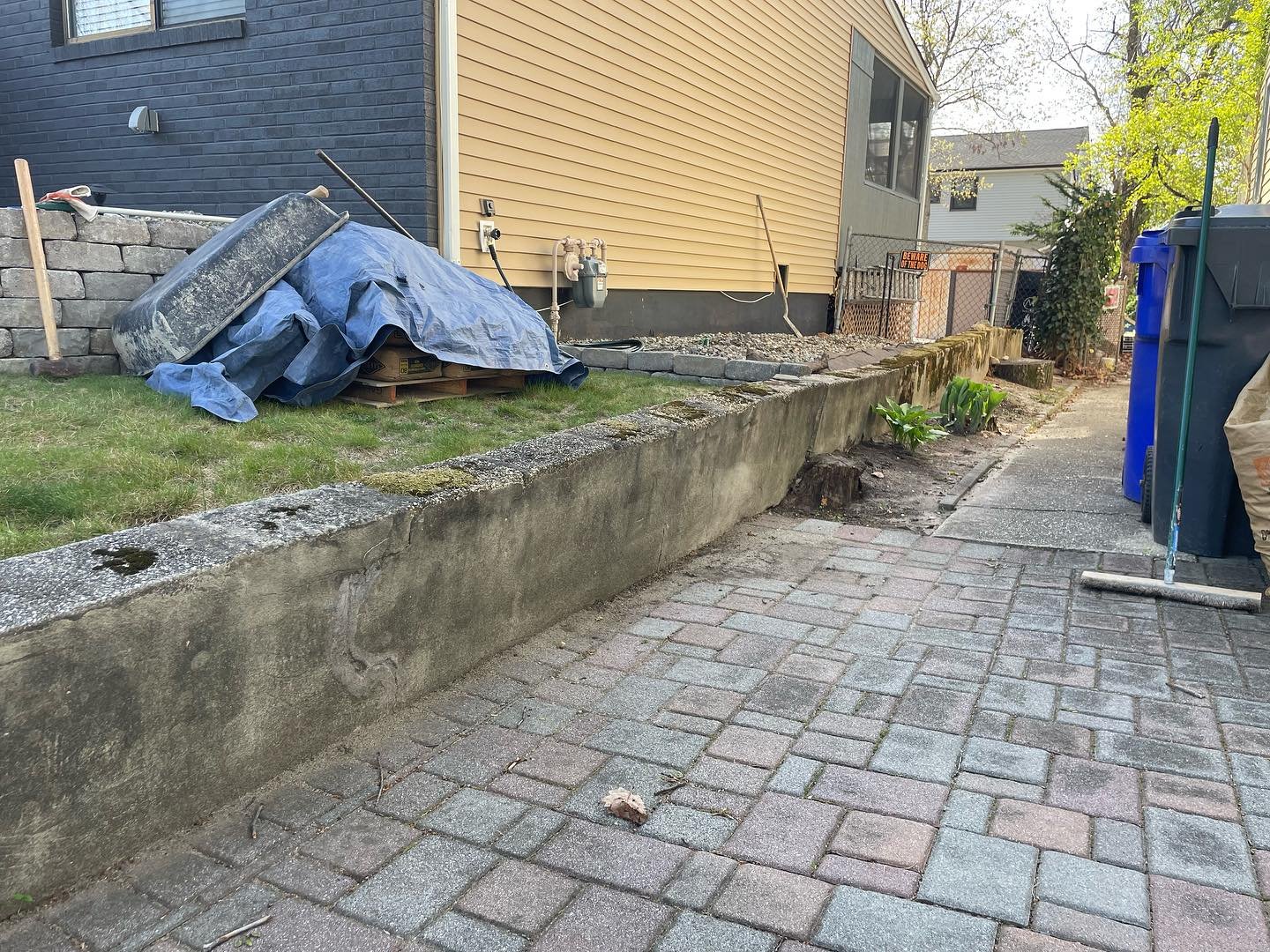 Before: the weathered concrete retaining wall beside the existing paver approach and raised lawn.
