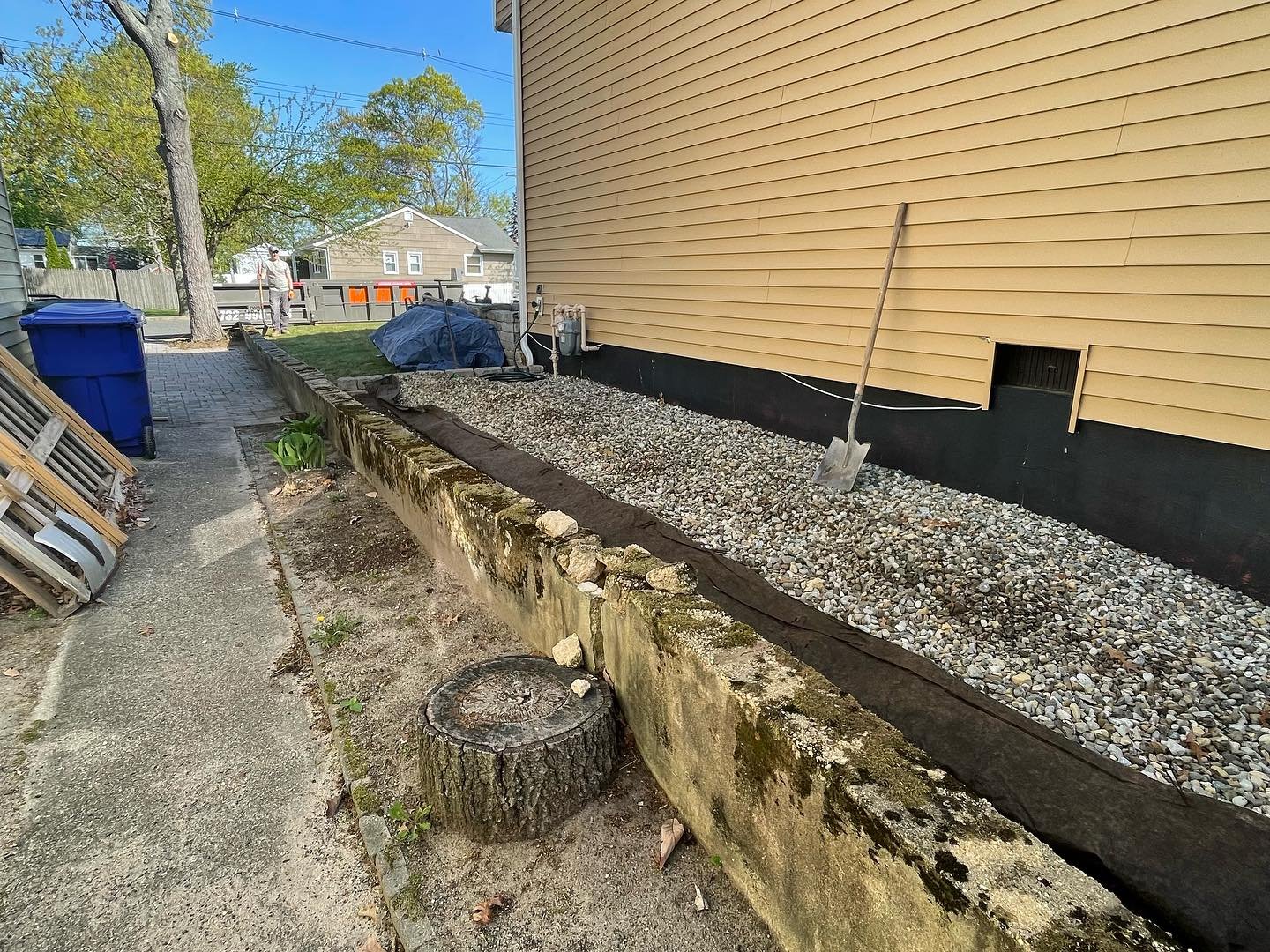 Before: the old wall viewed from the side passage, with a broken top edge and the gravel area beside the house.